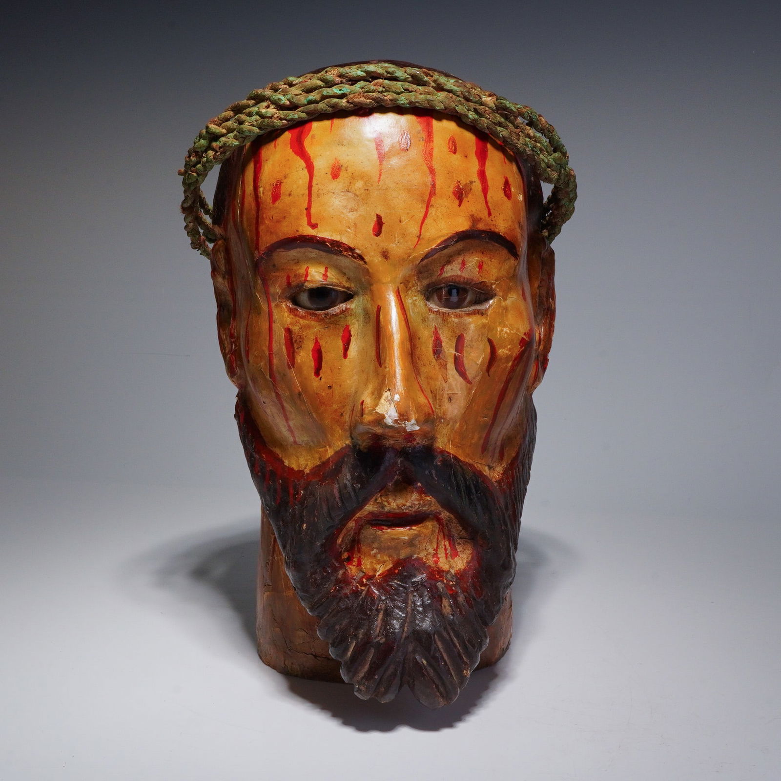 Spanish Colonial Polychrome Cristo Bust Fragment, 19th Century: This 19th-century Spanish Colonial polychrome bust of Christ is made of wood with a fiber crown. The carved wood head, likely a fragment from a larger devotional figure depicting the Man of Sorrows, f