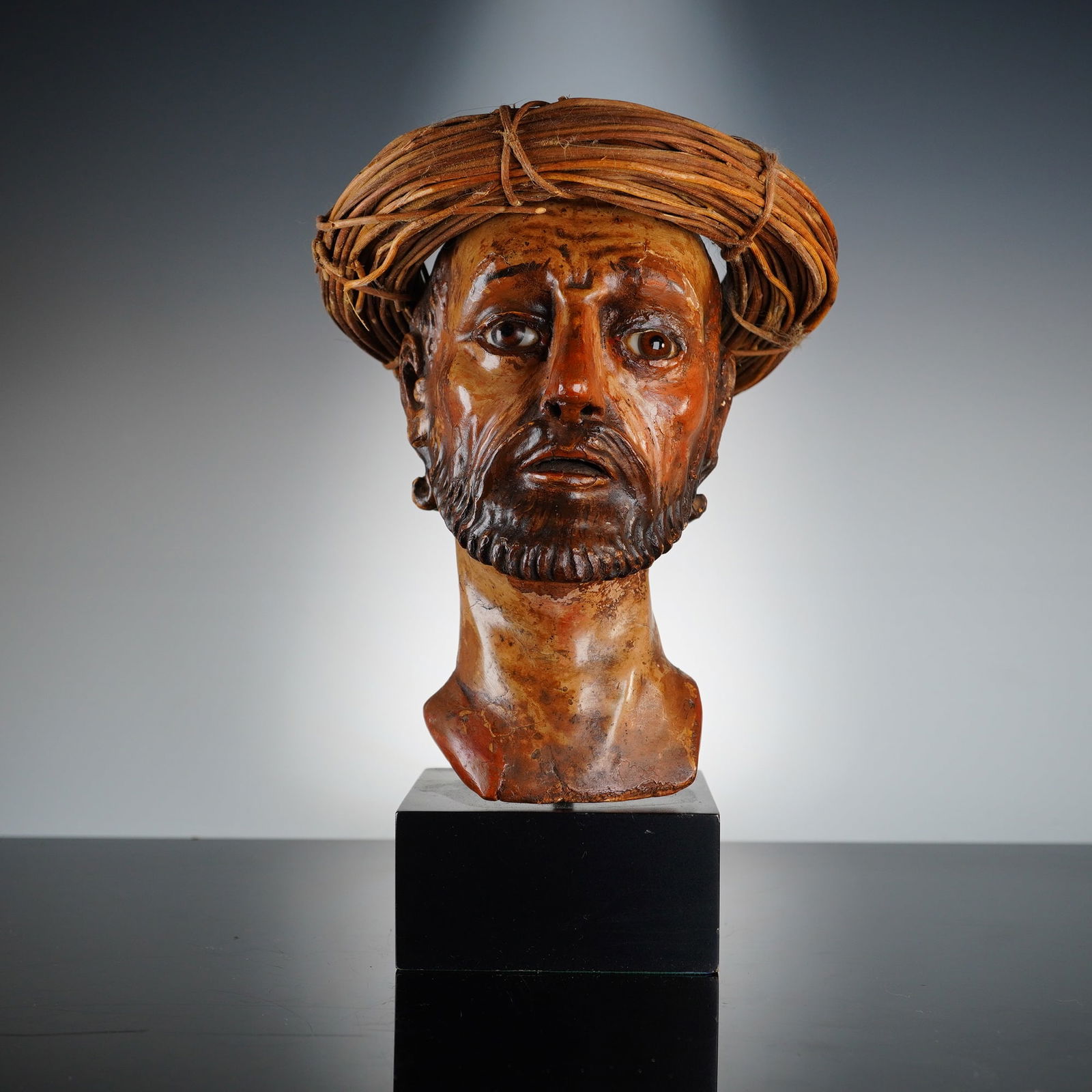 Spanish Colonial Carved Wood Devotional Bust of a Male Saint: This Spanish Colonial polychrome carved wood devotional bust of a male saint dates to the 18th or 19th century. The sculpture depicts a bearded male figure with expressive facial features and inset gl