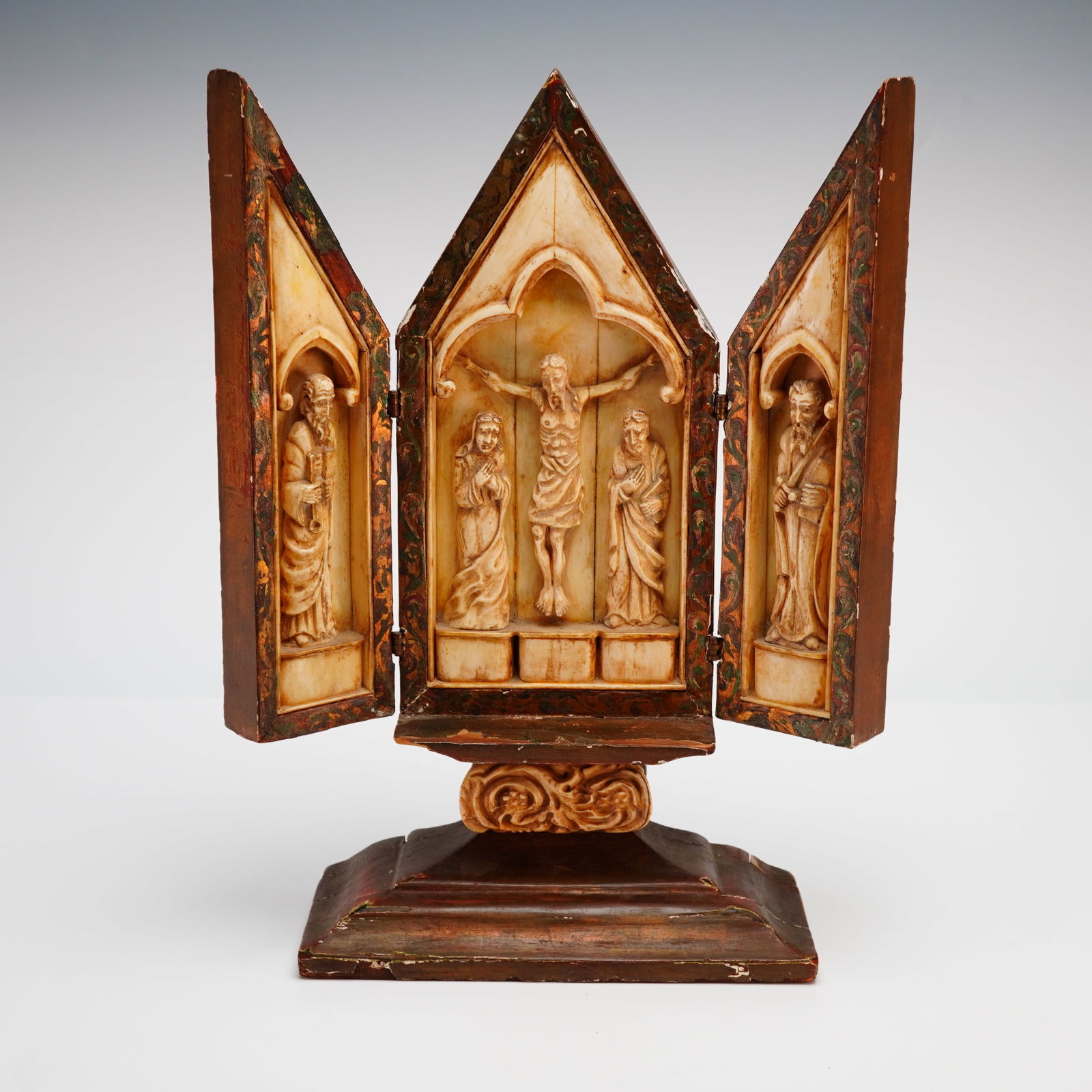 Neo-Gothic Religious Wood & Bone Triptych, The Crucifixion: Neo-Gothic triptych in carved wood and inlaid bone, The Crucifixion. This religious triptych features a central gabled panel depicting the Crucifixion of Christ in high relief, flanked by the mourning