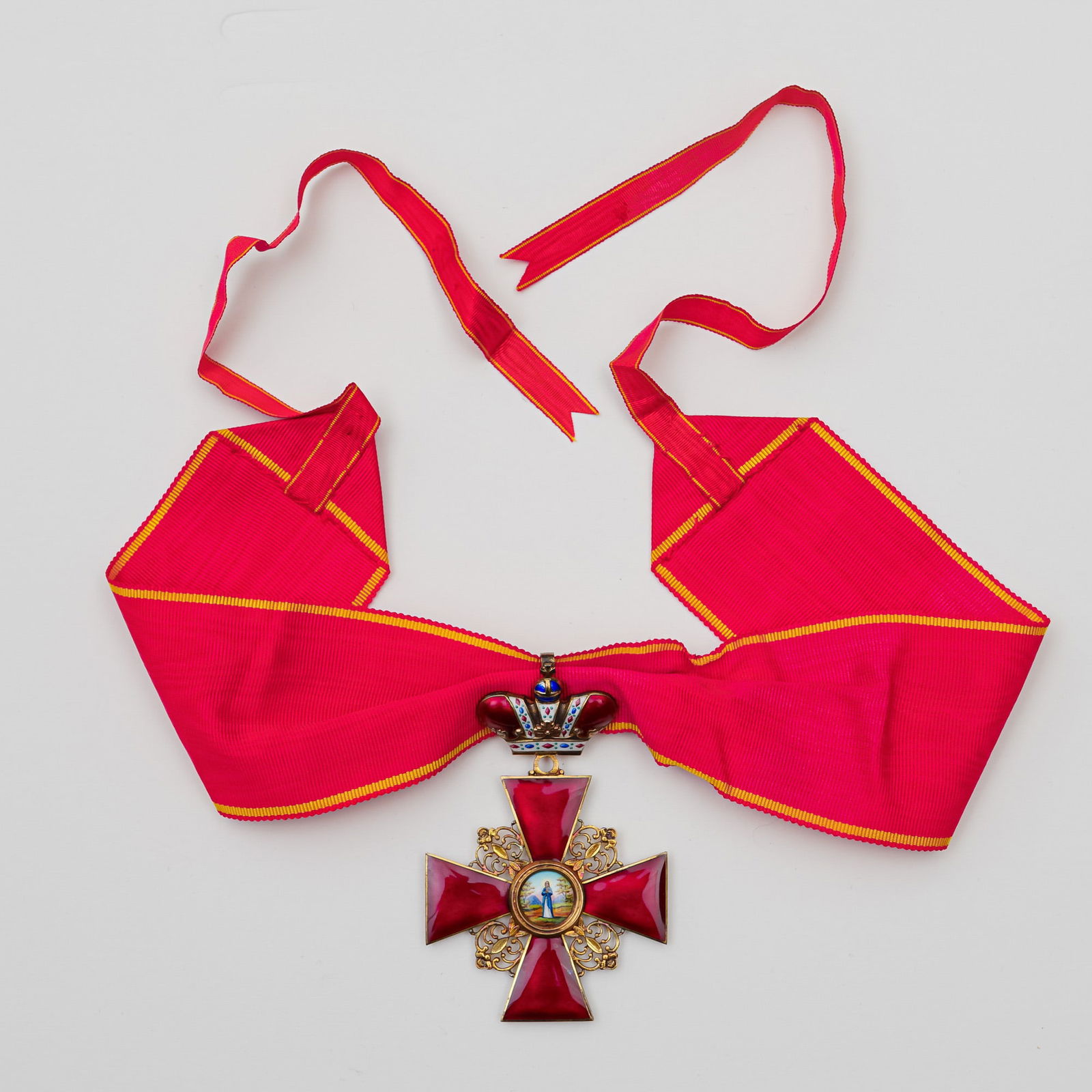 Russian Order of Saint Anna Badge, 3rd Class, Enamel on Bronze c.1801-1900: An Imperial Russian Order of Saint Anna, 3rd Class, crafted in translucent ruby-red enamel over finely gilded bronze. The four-pointed cross, framed with ornate pierced scrollwork, centers upon a beau