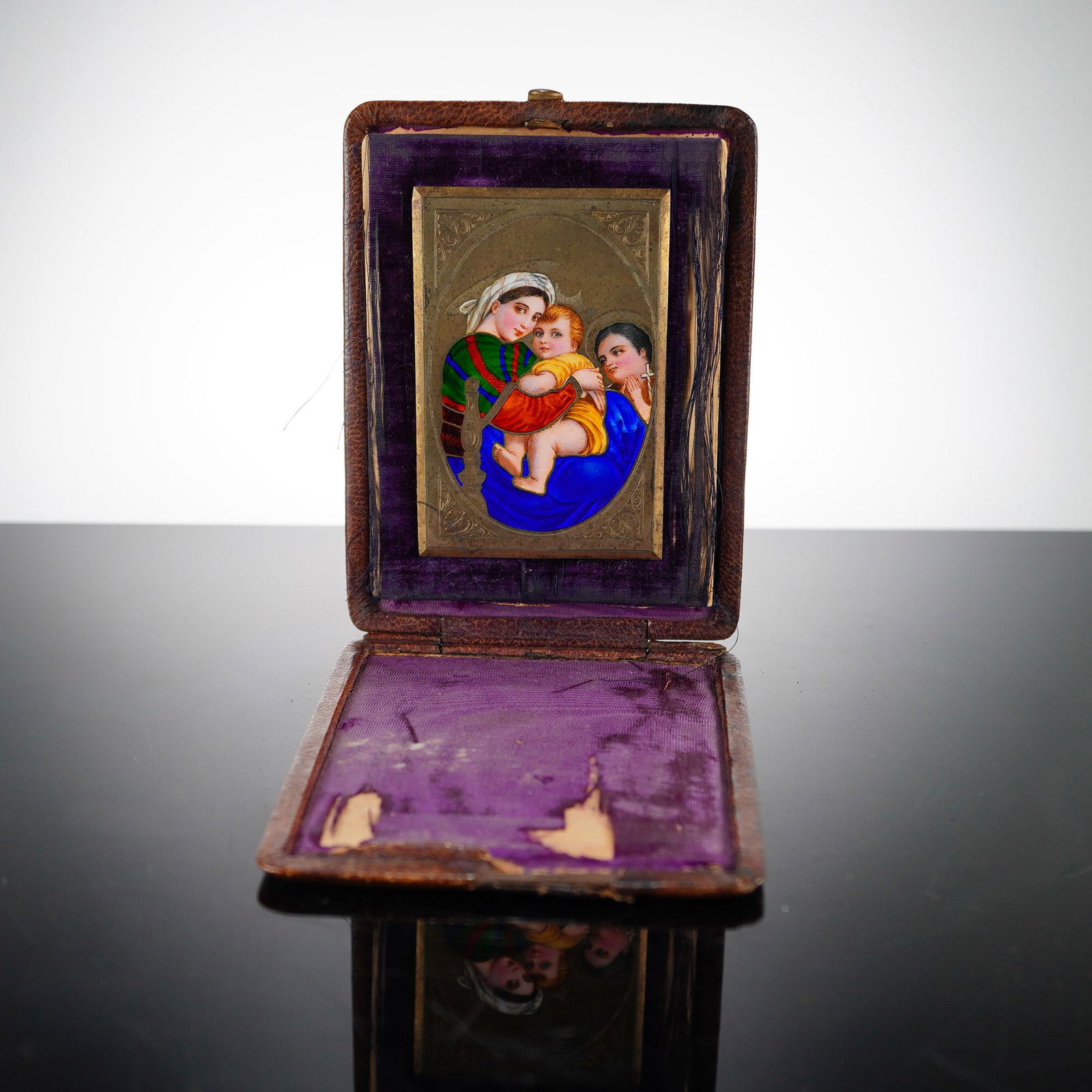 Portable Devotional Miniature Madonna and Child: Features a polychrome enamel painting on a thin metal plaque. The composition depicts the Madonna and Child with an attendant, rendered in a style influenced by Renaissance compositions. The figures a