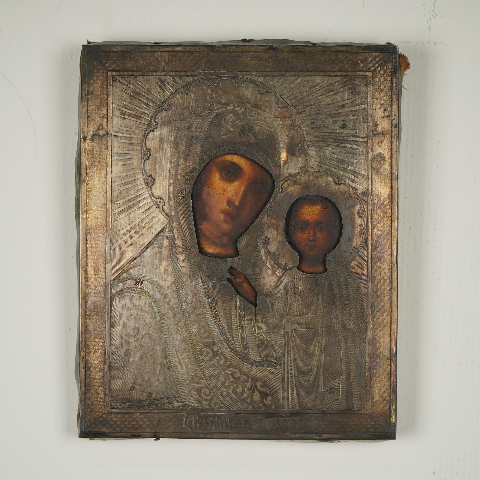 Russian Icon of Our Lady of Kazan with Gilt Silver Oklad: A Russian Orthodox religious icon depicting Our Lady of Kazan, executed in egg tempera on a wood panel overlaid with a decorative gilt silver oklad, featuring chased and engraved ornamentation. The Mo