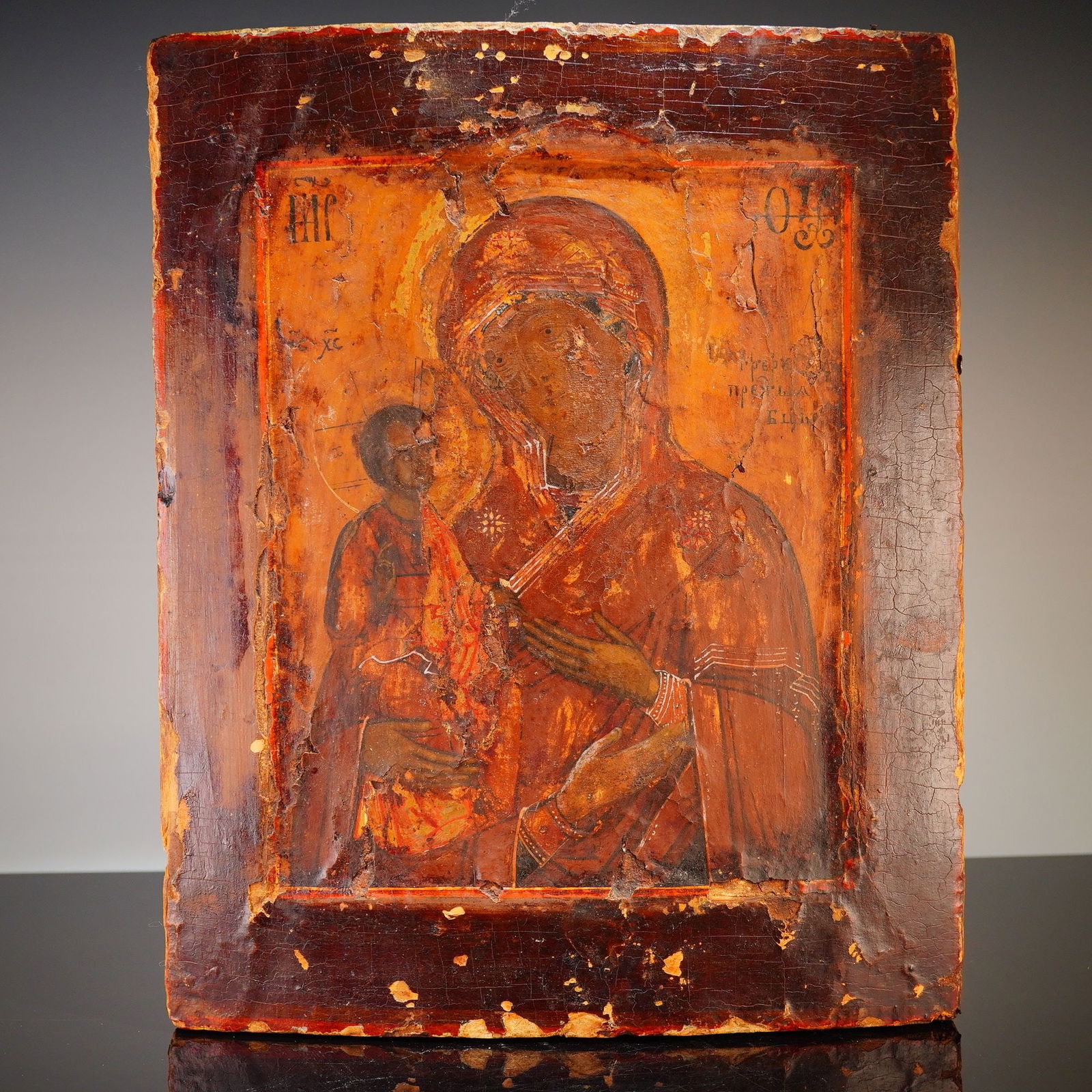 Russian Icon Painting on Wooden Panel Depicting the Madonna and Child: This Russian icon painting on wooden panel depicts the Virgin Hodegetria with the Christ Child. The work is executed in egg tempera and gesso on a solid wood support. The composition features traditio