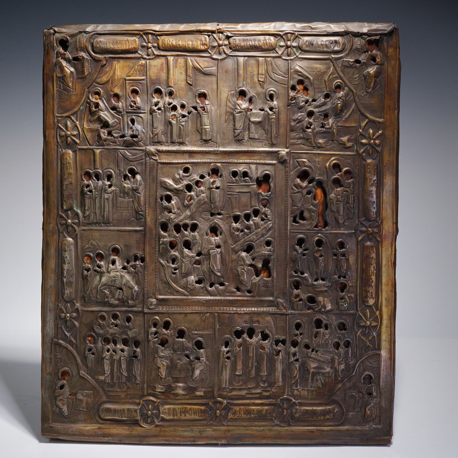 Russian Orthodox Icon Riza Mounted on Wood Panel: This 19th-century Russian Orthodox icon features a multi-scene narrative panel with a central Resurrection surrounded by twelve liturgical feast scenes. The wooden panel is overlaid with a heavily