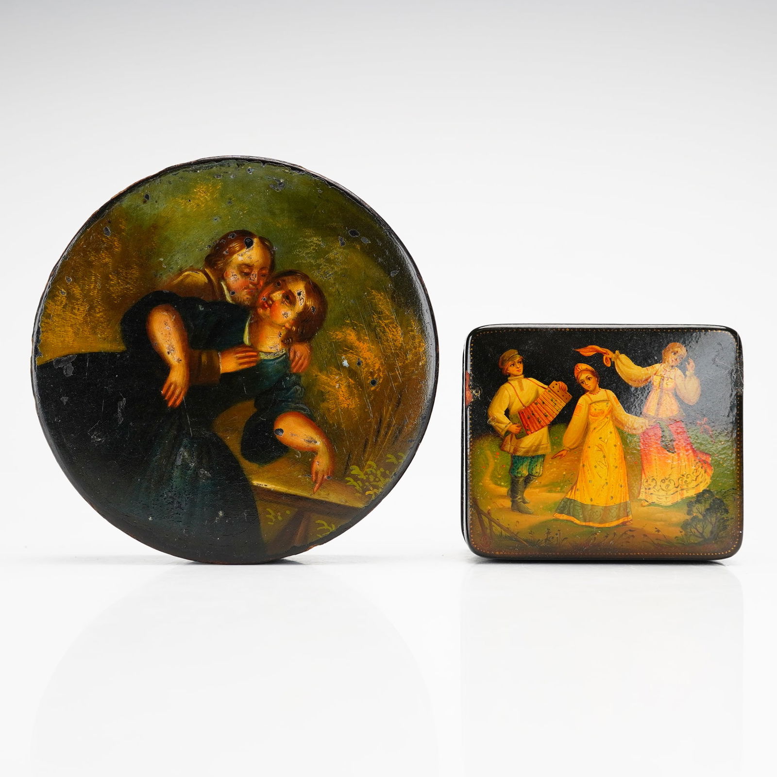 2pc Hand-Painted Lacquer Lidded Boxes: This lot consists of two lacquer boxes, including one Russian piece from Fedoskino. The set features a circular lidded box with a hand-painted scene on the lid depicting a couple in a period clothing,