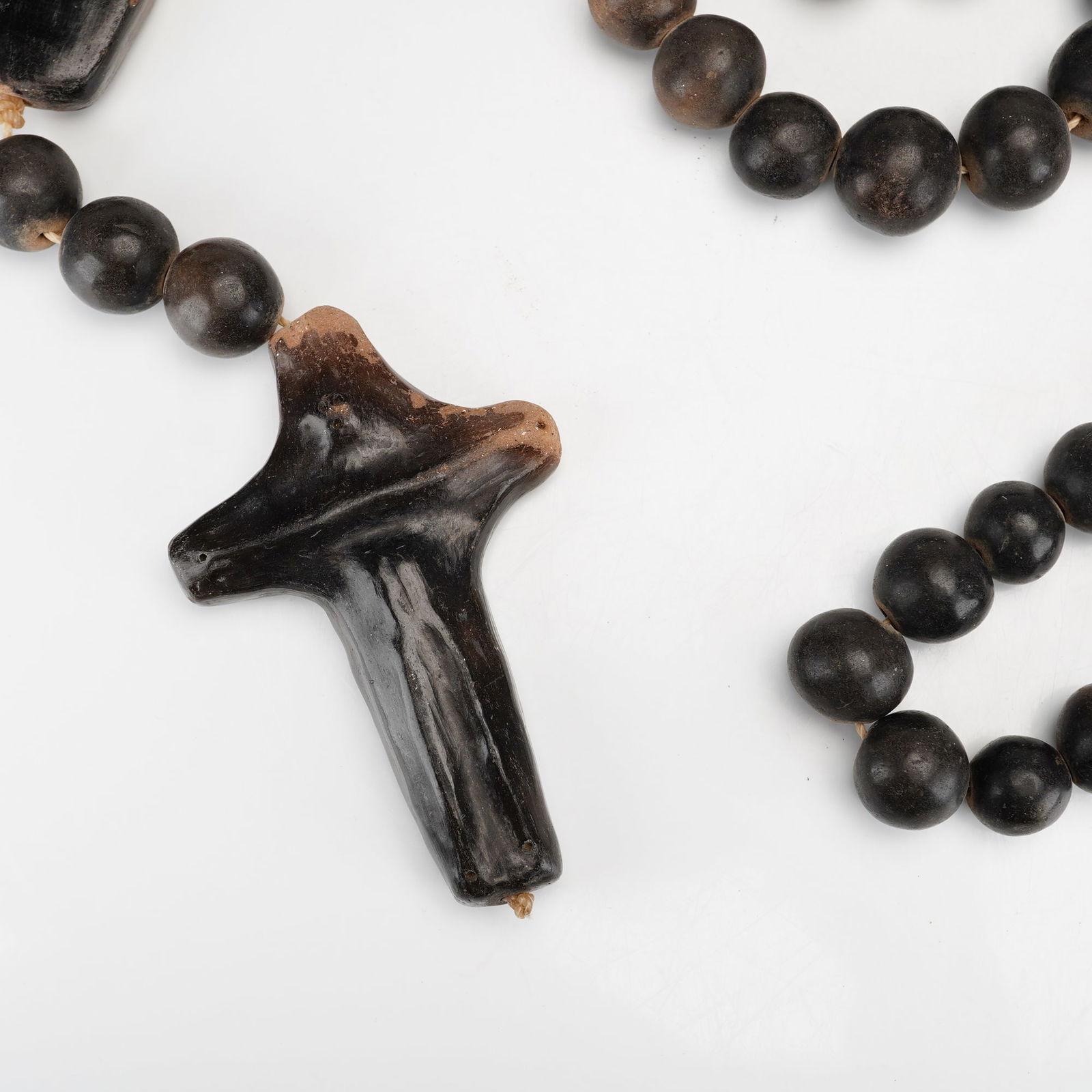 Brazilian Umbanda Handmade Wooden Prayer Beads with Cross Pendant: Featuring a combination of spherical dark brown to black beads and elongated cylindrical beads in a lighter brown tone. The assembly includes a stylized irregularly shaped cross pendant and a