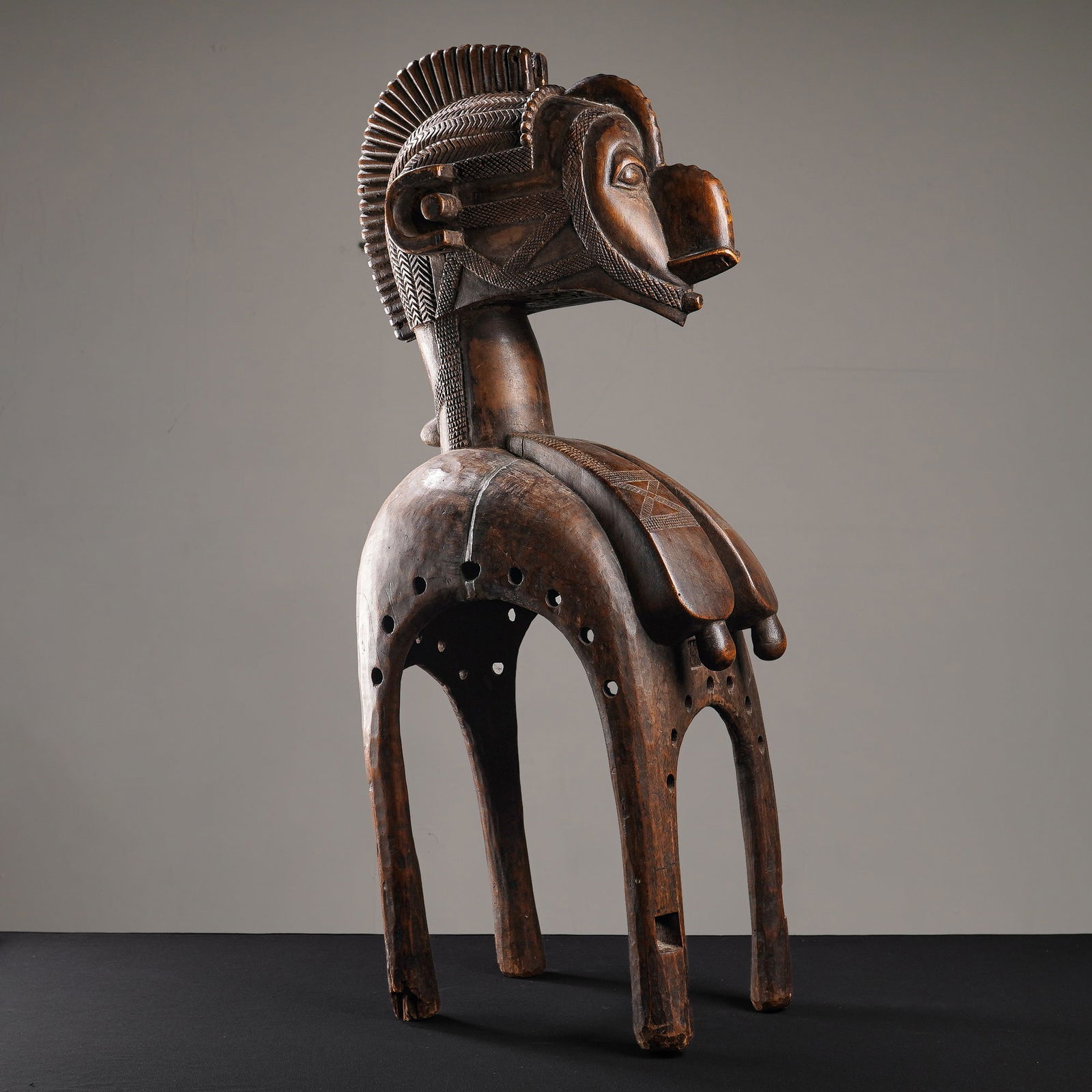 African Baga Nimba Wooden Ceremonial Shoulder Mask: From the Baga people of Guinea is a mask, hand-carved from a dark, patinated wood. Representing the Great Mother and bringing abundance, the sculpture features a stylized head with a curved nose, almo