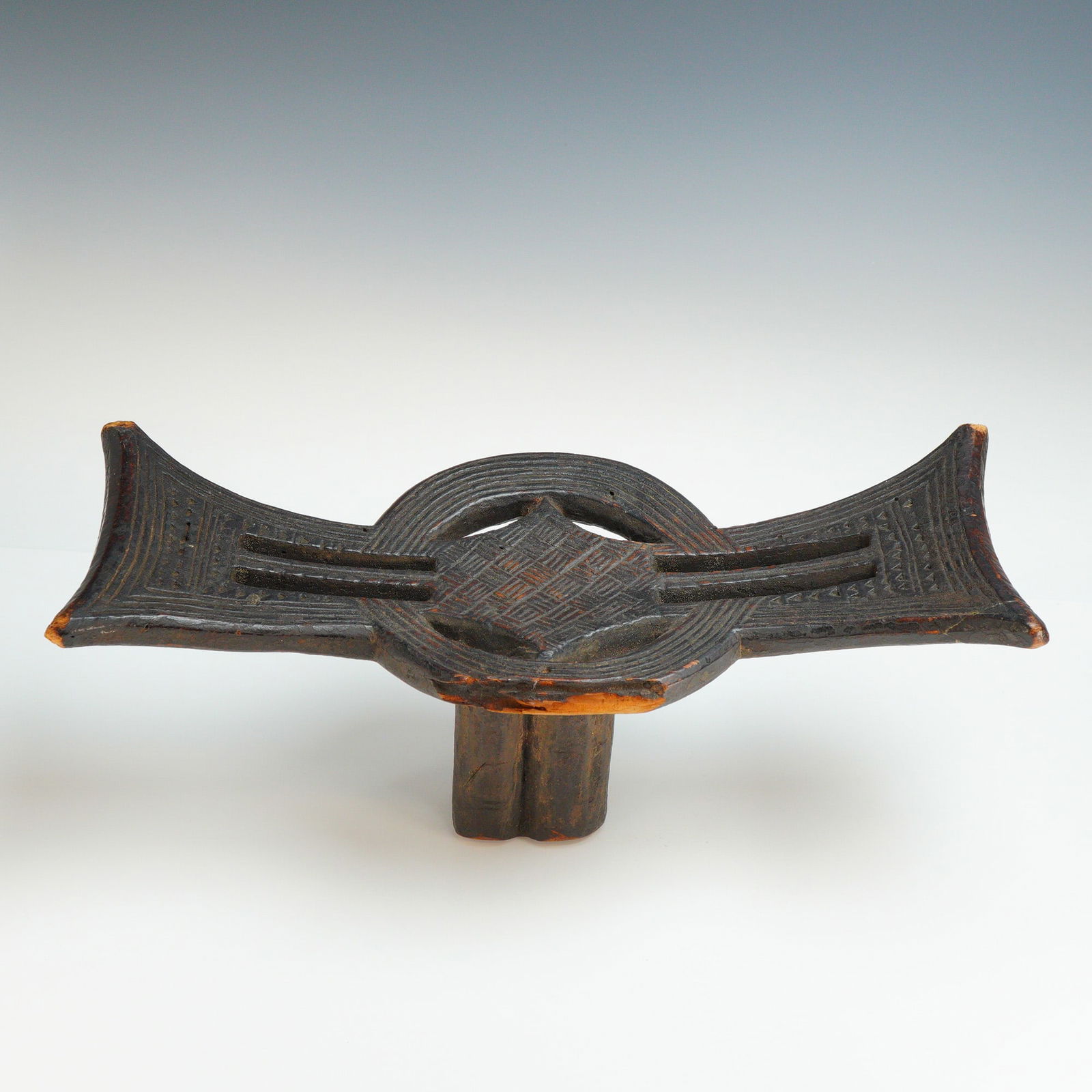 Antique Ethiopian Oromo African Carved Wooden Headrest: This African carved wooden headrest is attributed to the Oromo people of Ethiopia. Hand-carved from a single block of wood, the piece features a wide, concave top platform supported by a single, thick