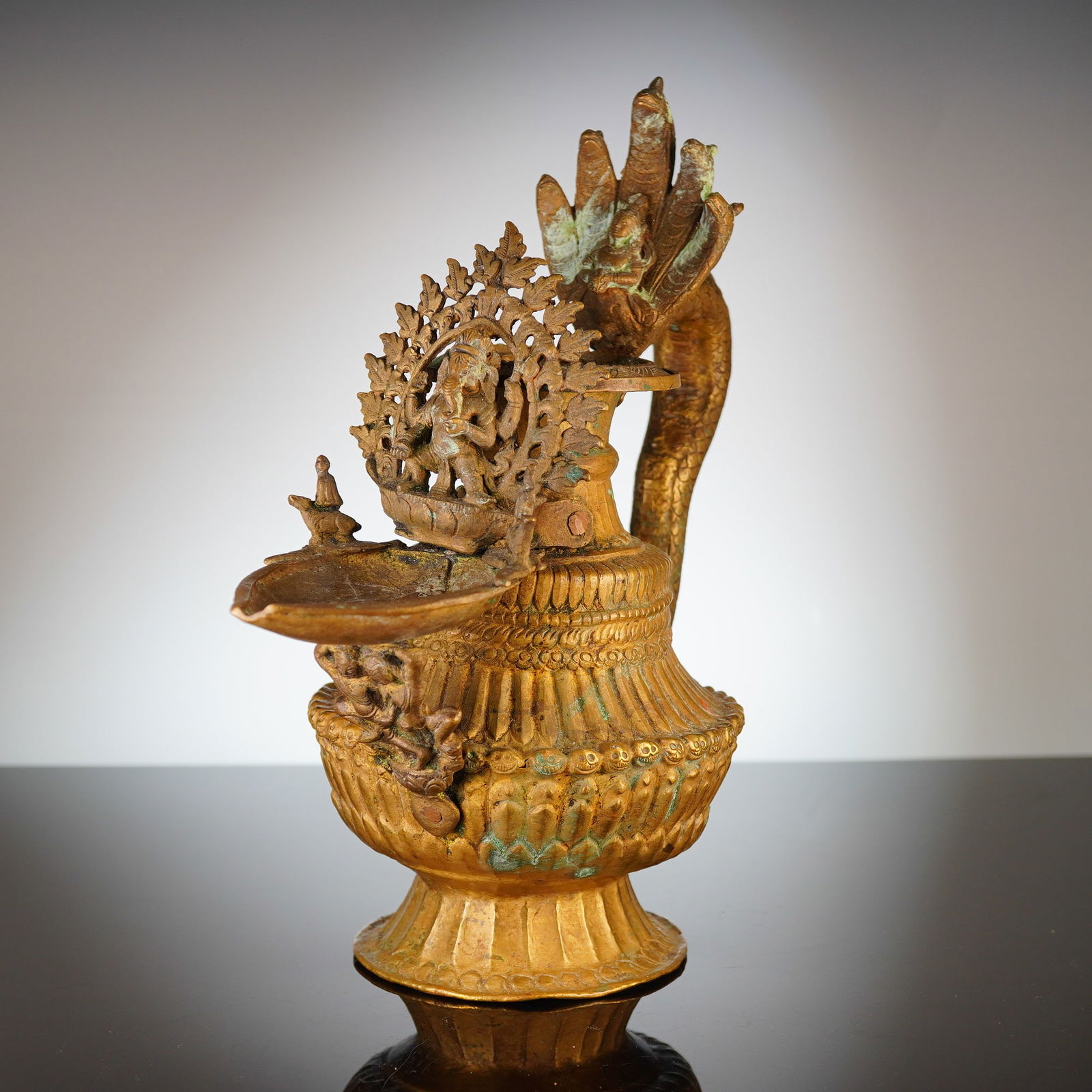 Nepalese Sukunda Ceremonial Brass Oil Lamp: This Nepalese Sukunda ceremonial brass oil lamp is cast from a copper-based alloy with a worn gold-tone finish. The vessel is a ritual oil lamp featuring a projecting reservoir at the front backed by