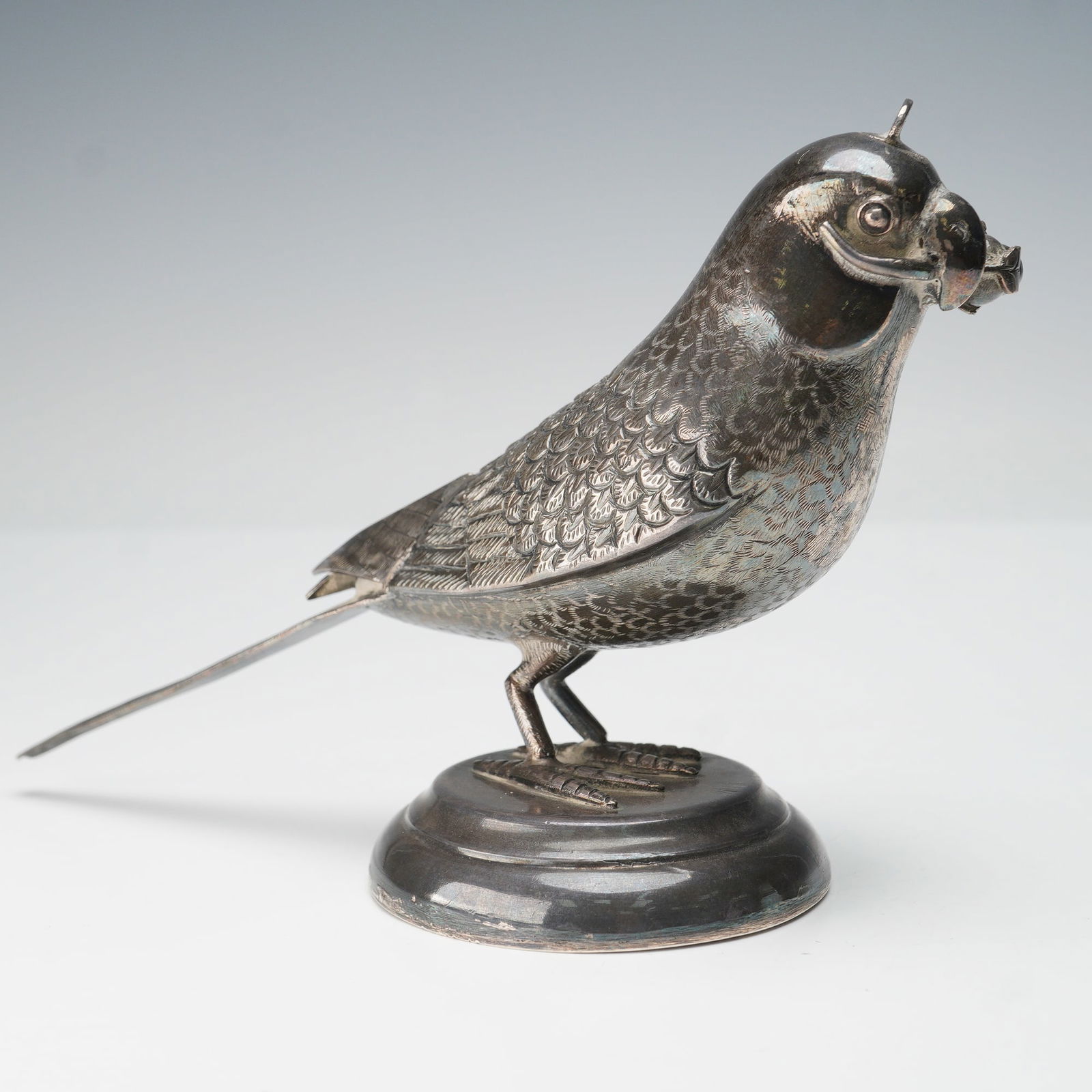 Indian Silver Parrot Form Rose Water Sprinkler: An Indian silver rose water sprinkler fashioned in the form of a parrot, meticulously detailed with chased and engraved plumage capturing the naturalistic texture of feathers. The bird stands poised
