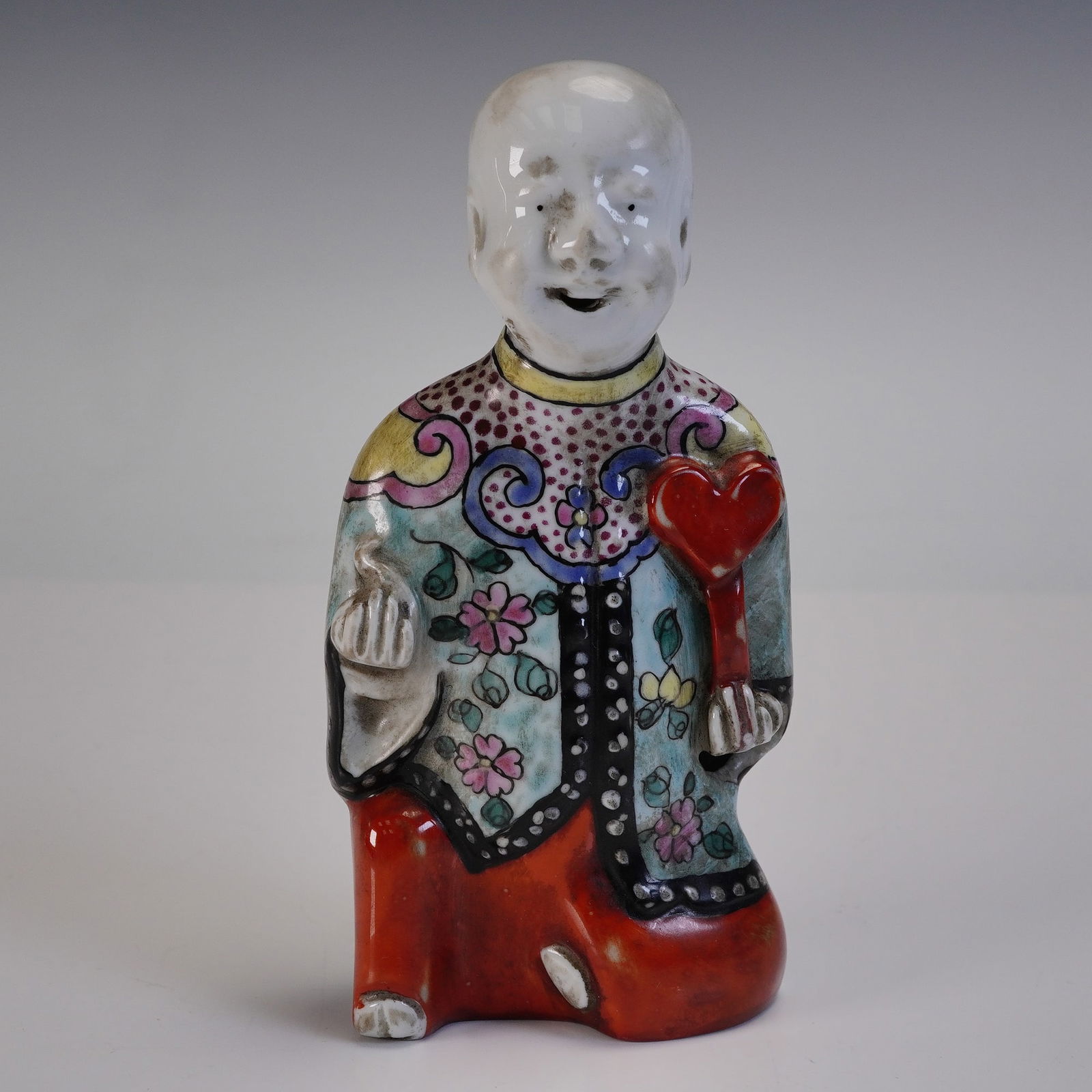 Chinese Famille Rose Porcelain Joss Stick Holder: Chinese Famille Rose porcelain joss stick holder depicting a seated male figure. The figure is shown holding a ruyi scepter in the right hand and a small object in the left hand. He wears a robe decor