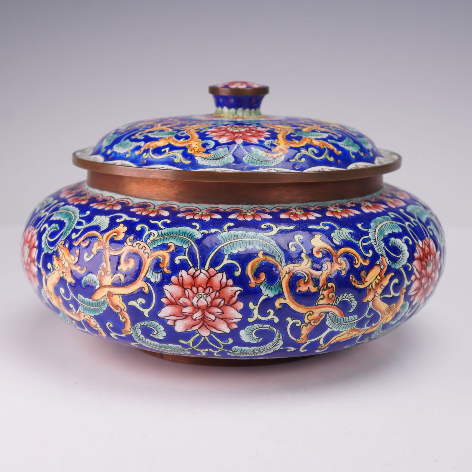 2pc Chinese Canton Enamel Vanity Box with Lid: The circular box is decorated with polychrome floral and vine patterns on a blue ground, featuring pink lotus blossoms, scrolling foliage, and stylized dragons in yellow and orange tones. The lid is s