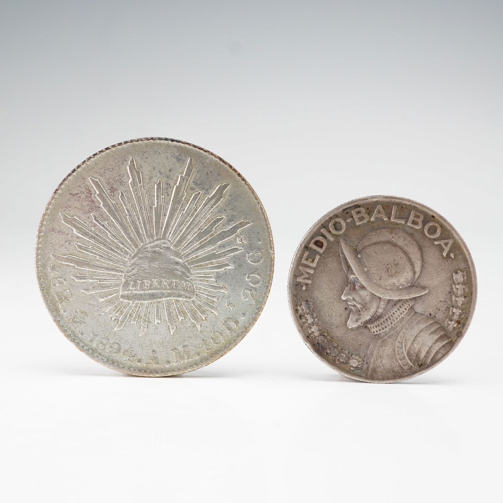 2pc 1894 Mexico 8 Reales & 1934 Panama Half Balboa Silver Coins: Comprises one Mexican 8 Reales crown and one Panamanian 1/2 Balboa. The Mexican currency obverse showcases an eagle with snake on cactus while the reverse features radiant cap with rays,