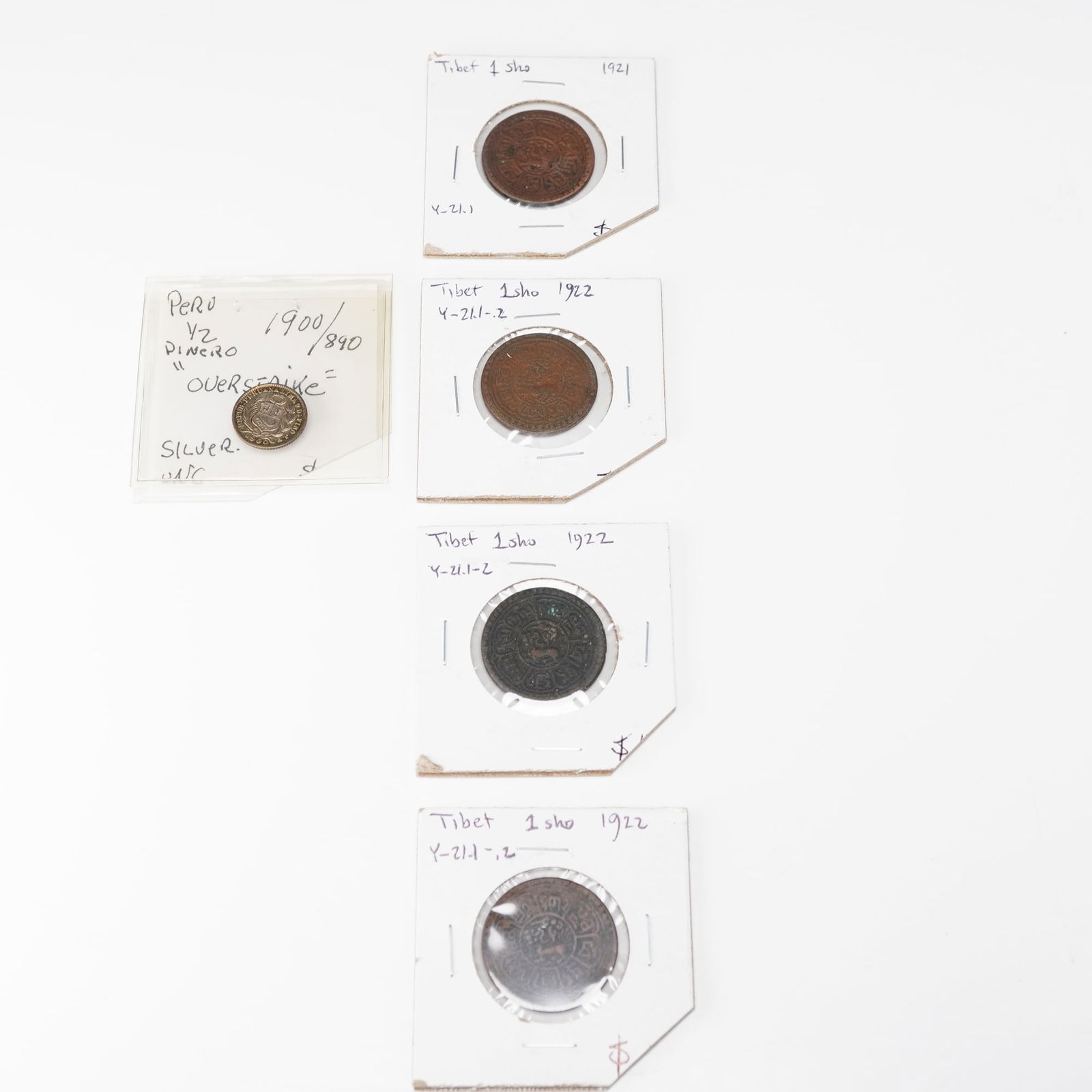 5pc Tibetan 1921 to 1922 1 Sho & Peruvian 1900 1/2 Dinero Coins: Each Tibetan coin featuring a central snow lion motif on the obverse surrounded by Tibetan script, with reverse inscriptions arranged in circular legend designs; struck in copper at regional Tibetan