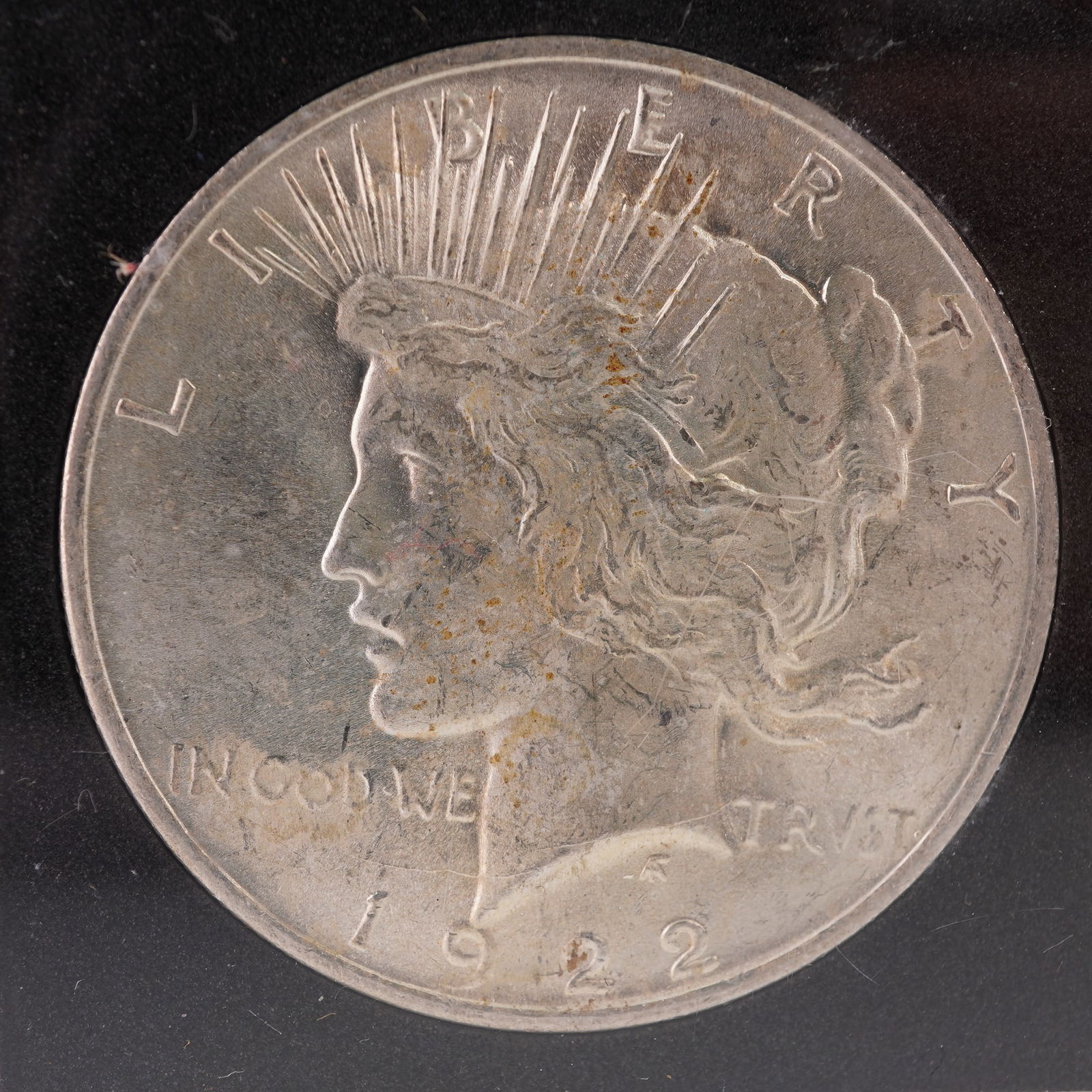 1922 Peace Silver Dollar: Presented in a protective case, this 1922 Peace Silver Dollar features the artistry of Anthony de Francisci. The front of the coin portrays Liberty facing left with a radiate crown above her head,