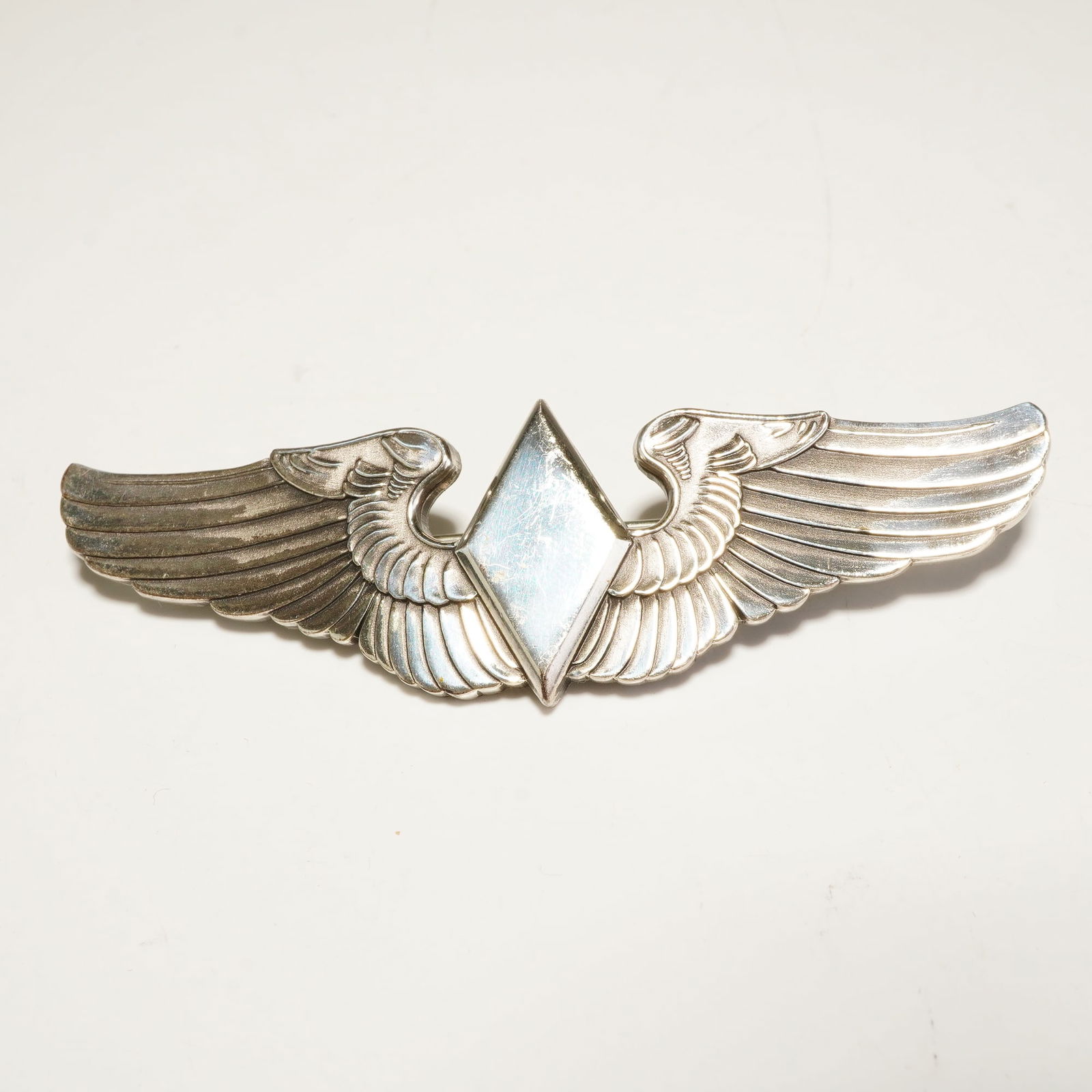 WWII Jostens Sterling Silver Women Airforce Service Pilots Pilot Wing Badge: This World War II-era Women Airforce Service Pilots (WASP) pilot wing badge is manufactured by Jostens and struck in sterling silver. The design features a central diamond-shaped lozenge with a polish
