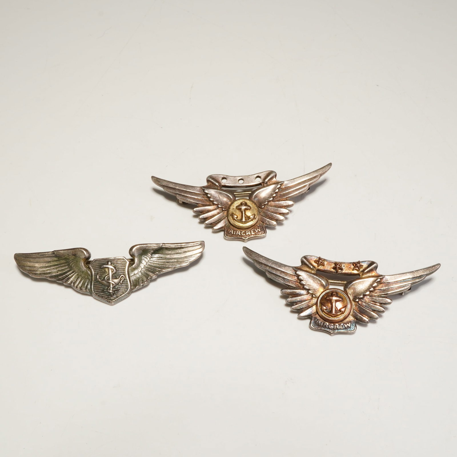 3pc WWII USMC Aircrew USAF Flight Surgeon Sterling Wing Pins: This three-piece lot consists of two U.S. Marine Corps Aircrew wing pins and one U.S. Air Force Flight Surgeon pin. The Aircrew wings feature central anchor emblems; one badge is further distinguished