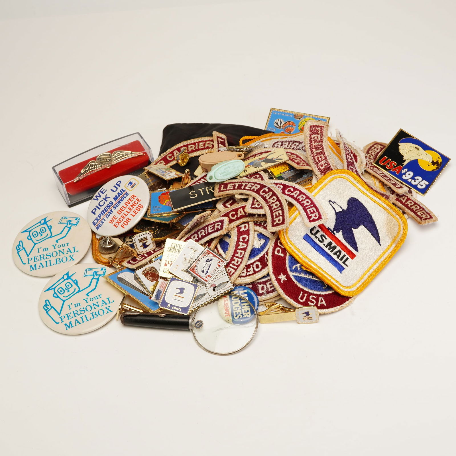 Assortment of U.S. Mail Patches, Pins, and Buttons, Circa 1960s-1990s: This lot consists of a diverse assortment of United States Postal Service (USPS) and Letter Carrier memorabilia, primarily dating from the 1960s through the 1990s. The collection includes numerous emb
