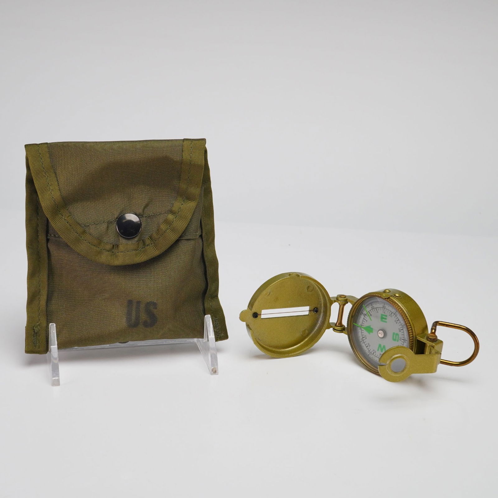 US Military, Army and USMC, Lensatic Compass with US Military First Aid Compass Case, Cold War Era: This lot features a US military-style lensatic compass paired with a genuine issue US Military First Aid Compass carrying case. The compass is a liquid-damped model finished in a metallic olive-gold t