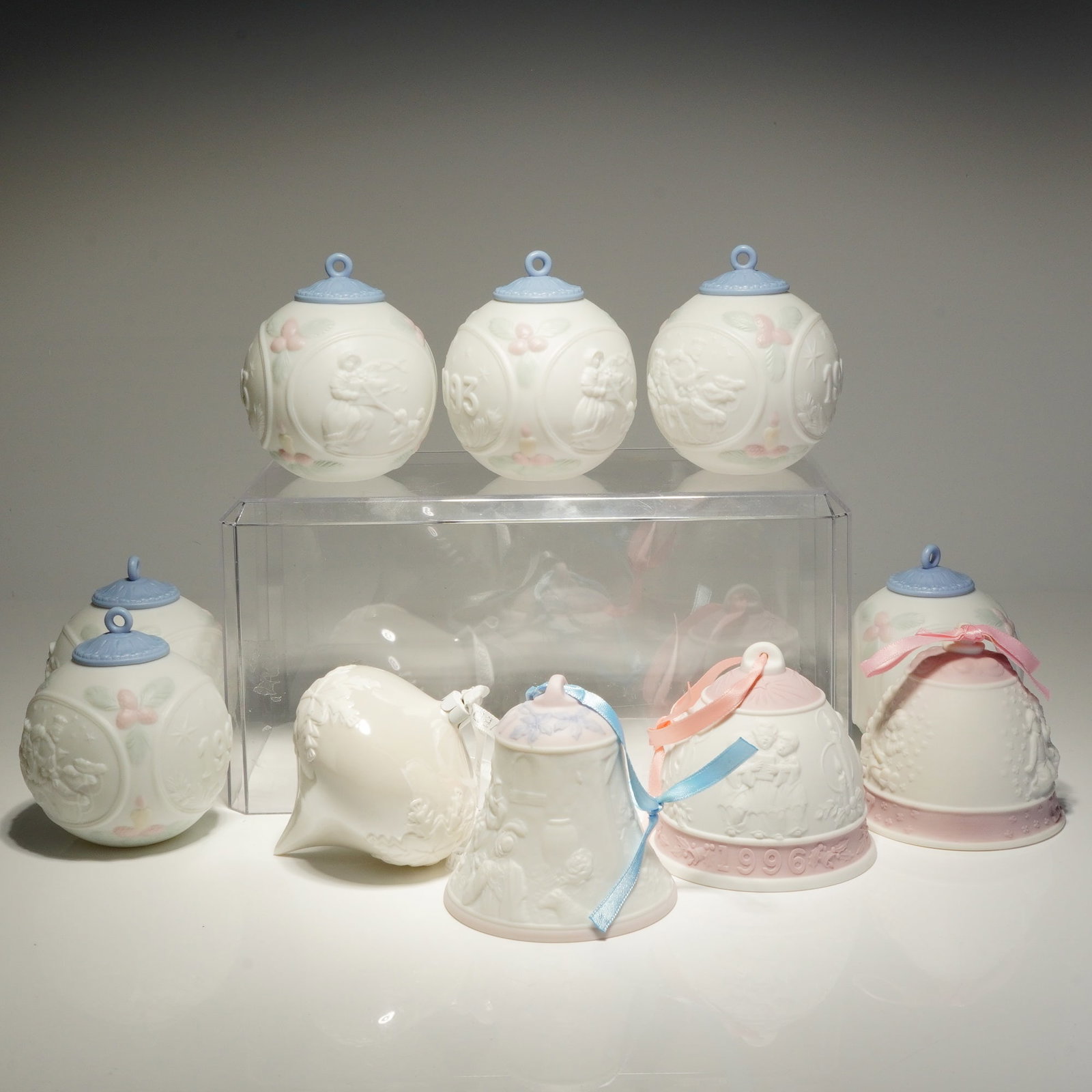Collection of Ten Lladro and Wedgwood Porcelain Christmas Ornaments: Assorted bisque porcelain ornaments featuring various bell and sphere forms. The ornaments are decorated with bas-relief scenes depicting figures, such as carolers, and floral motifs, accented with pa