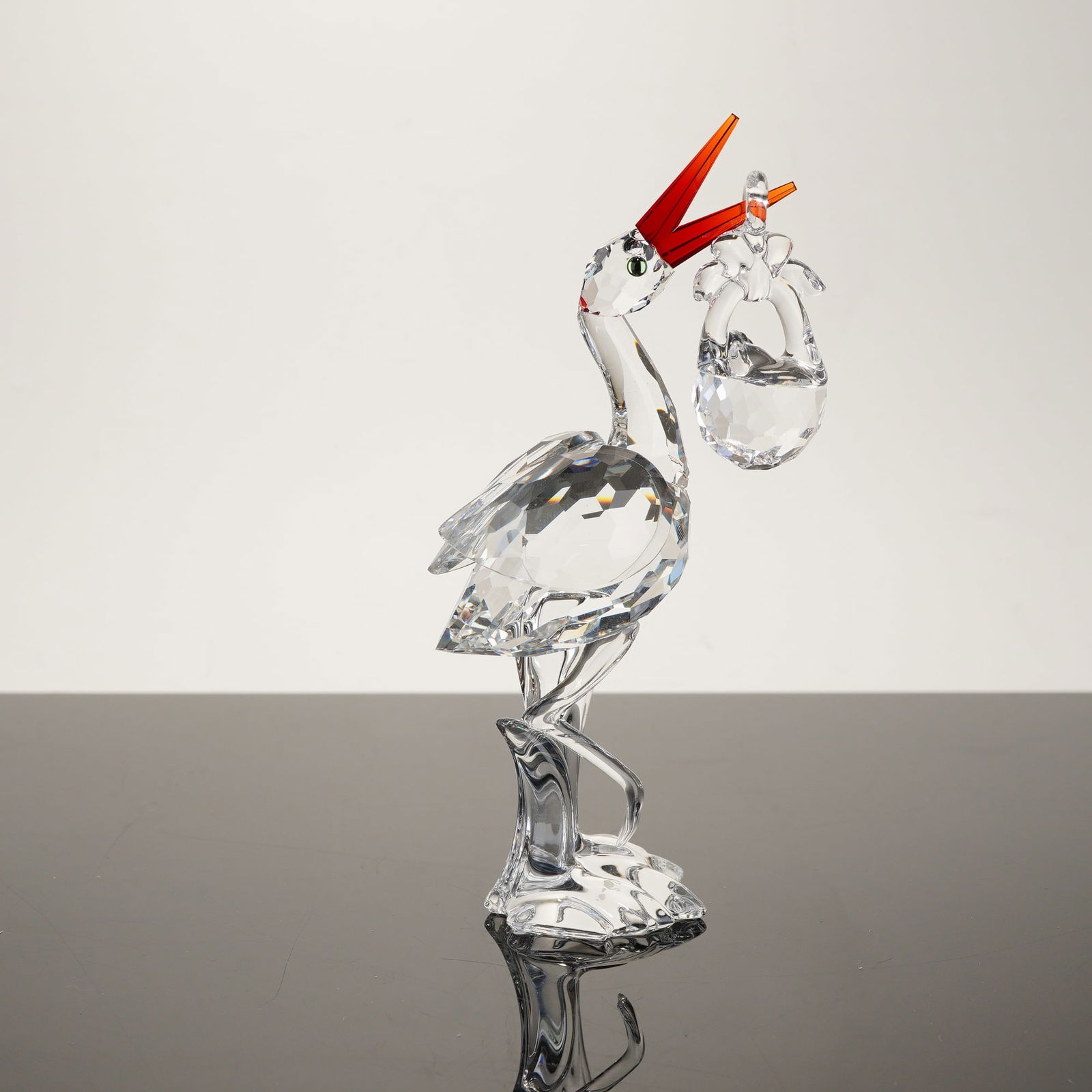 Swarovski Crystal Stork with Baby Figurine, Model 659401: This Swarovski crystal figurine, titled Stork with Baby, was designed by Anton Hirzinger as part of the When We Were Young collection. The piece features a stylized stork crafted from fine faceted lea