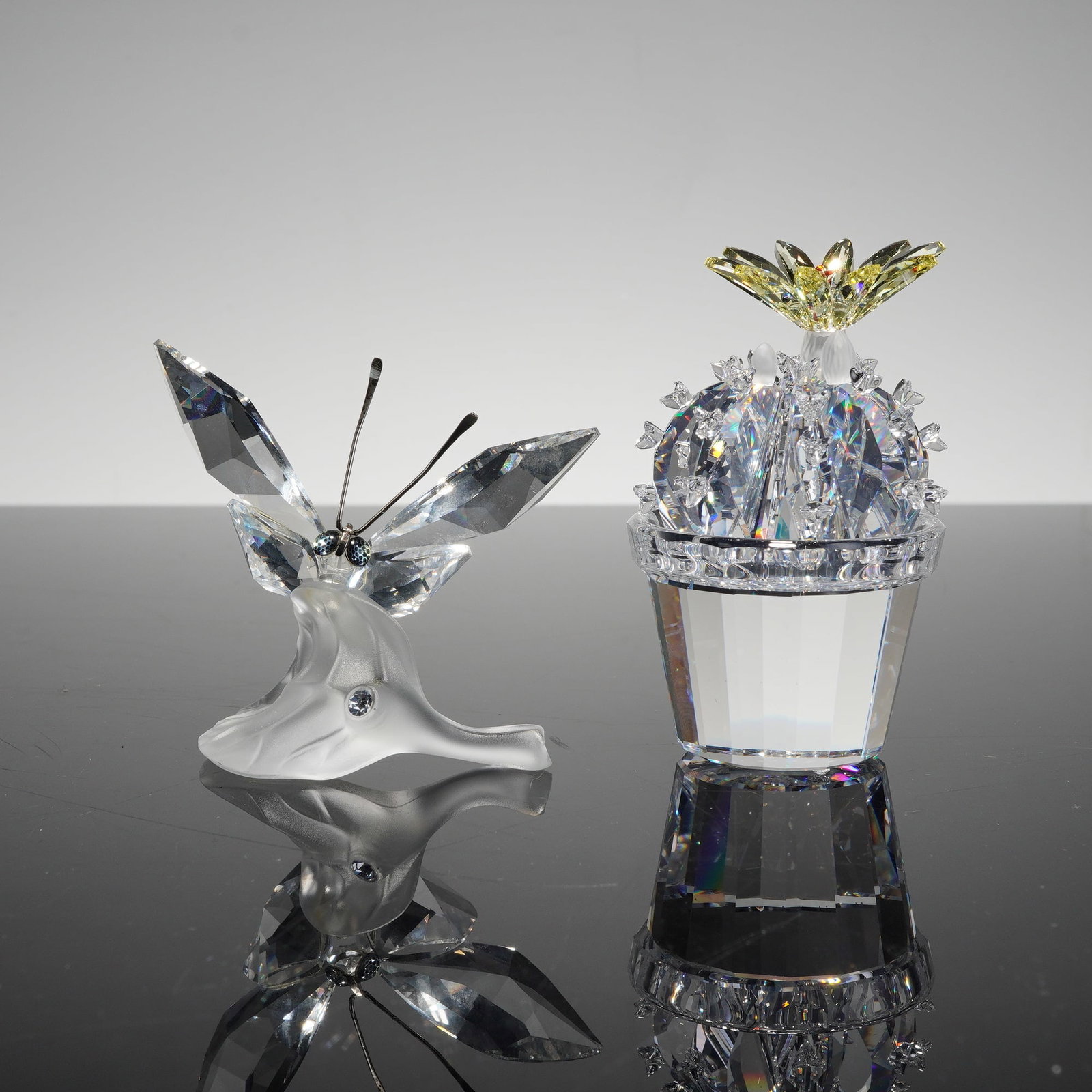 Swarovski Crystal Figurines, Butterfly on Leaf 182920 and Flowering Cactus 291549: A pair of Swarovski Silver Crystal figurines featuring the "Butterfly on Leaf" (model 182920) and the "Flowering Cactus" (model 291549). The butterfly is designed with clear faceted crystal wings, dar