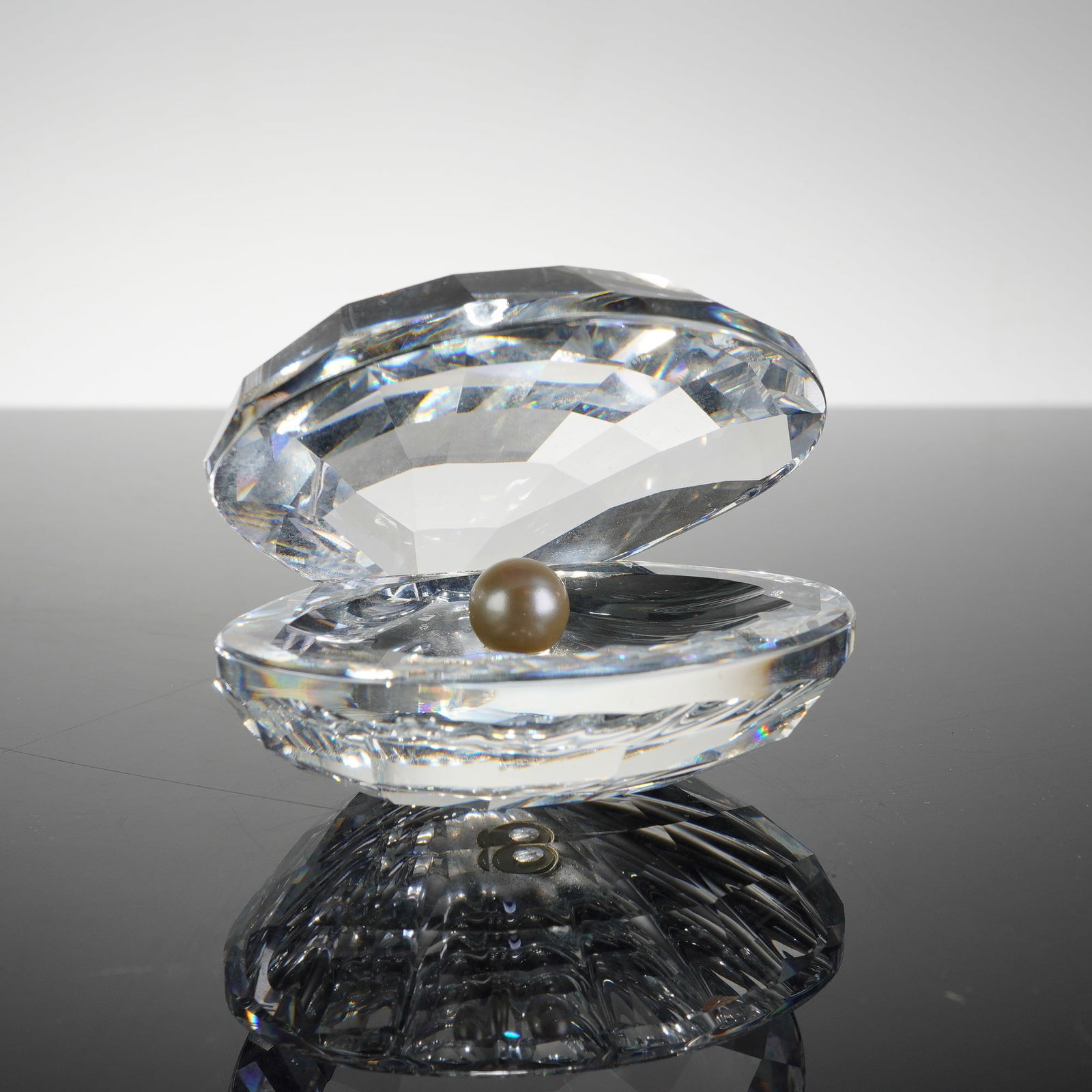 Swarovski Silver Crystal Oyster Shell with Pearl Figurine: This Swarovski Crystal Figurine, Oyster Shell with Pearl, is a distinguished piece from the Silver Crystal collection. Designed by Michael J. Stamey (model 014389), the figurine depicts an open oyster