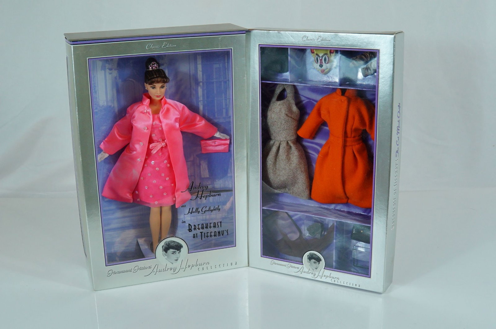 A Pair of Mattel Audrey Hepburn Breakfast at Tiffany's Holly Golightly 11.5" Doll and Fashion Set: This offering features two factory-sealed items from the 1998 Mattel Audrey Hepburn Collection, Classic Edition, inspired by the film Breakfast at Tiffany's. The first item is the Holly Golightly