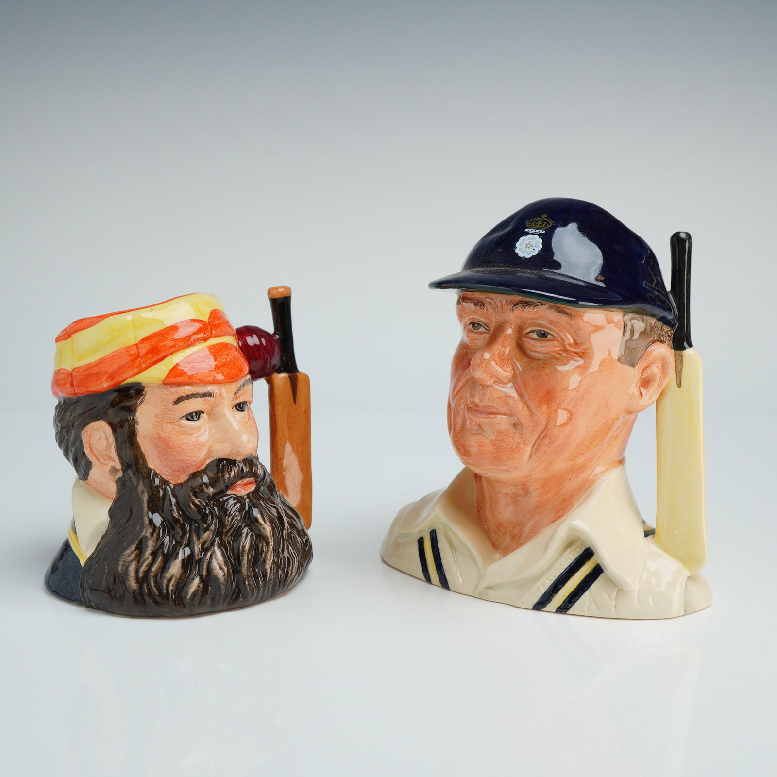 Two Royal Doulton Small Character Jugs, D6845 and D6739: Two Royal Doulton limited edition ceramic character jugs depicting prominent cricketing figures. The first jug, titled The Champion W.G. Grace (D 6845), was modeled by Stanley James Taylor and issued