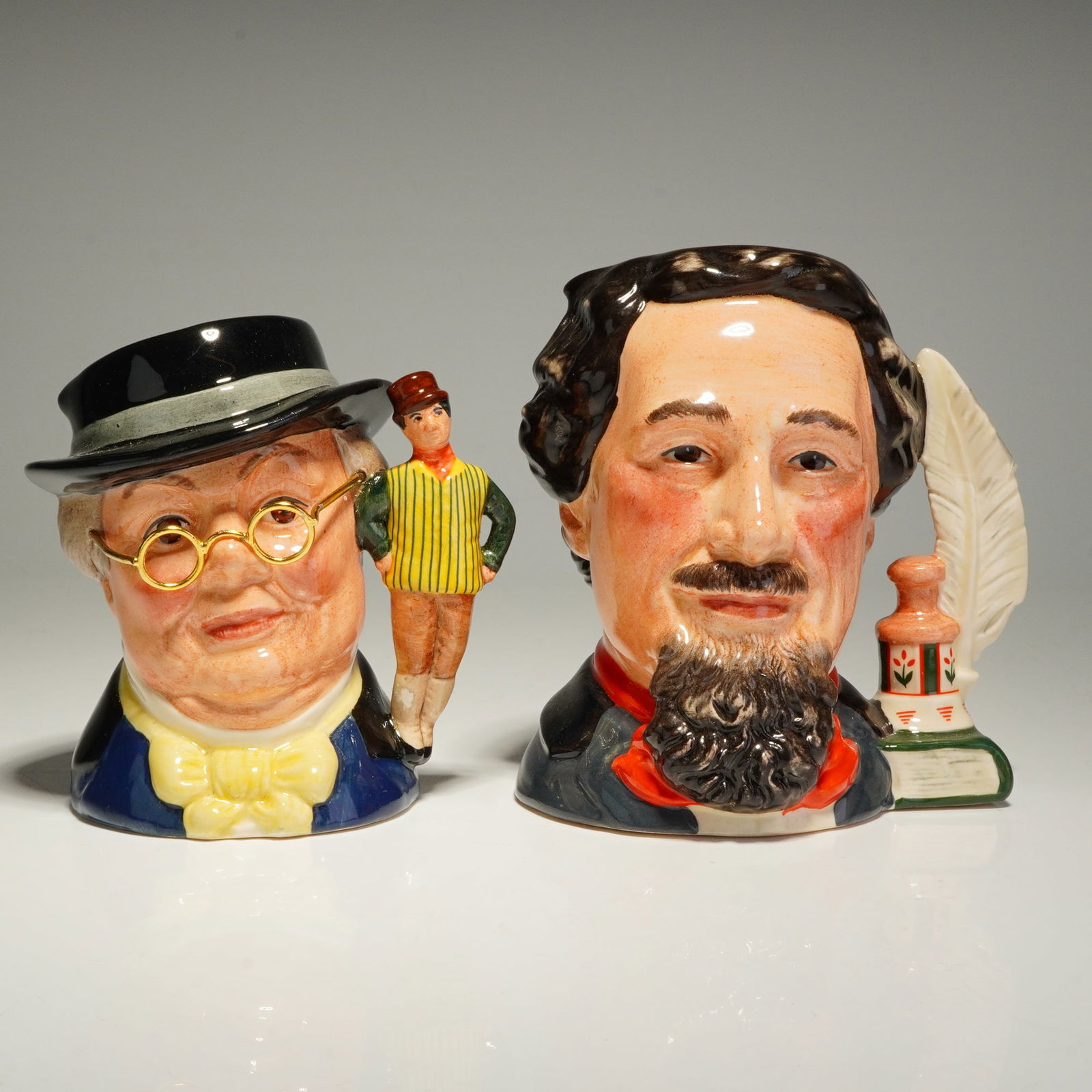 2pc Royal Doulton Small Character Jugs, D6901 and D7025: Character jugs crafted in glazed ceramic with a high-gloss finish. The first item is a Charles Dickens D6901 small, limited edition jug, numbered 4447 of 7,500. Modeled by William K. Harper for the In