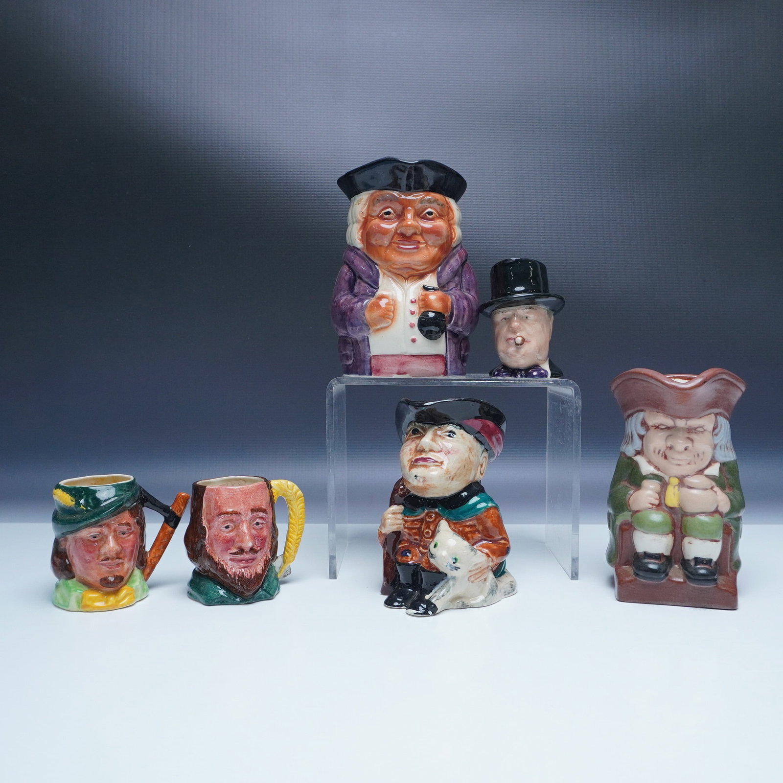 6pc English Porcelain Toby and Character Jugs: This lot includes six delightful English porcelain Toby and character jugs, crafted by Lancaster and Staffordshire. Each jug showcases vibrant hand-painted detailing and unique character portraits,