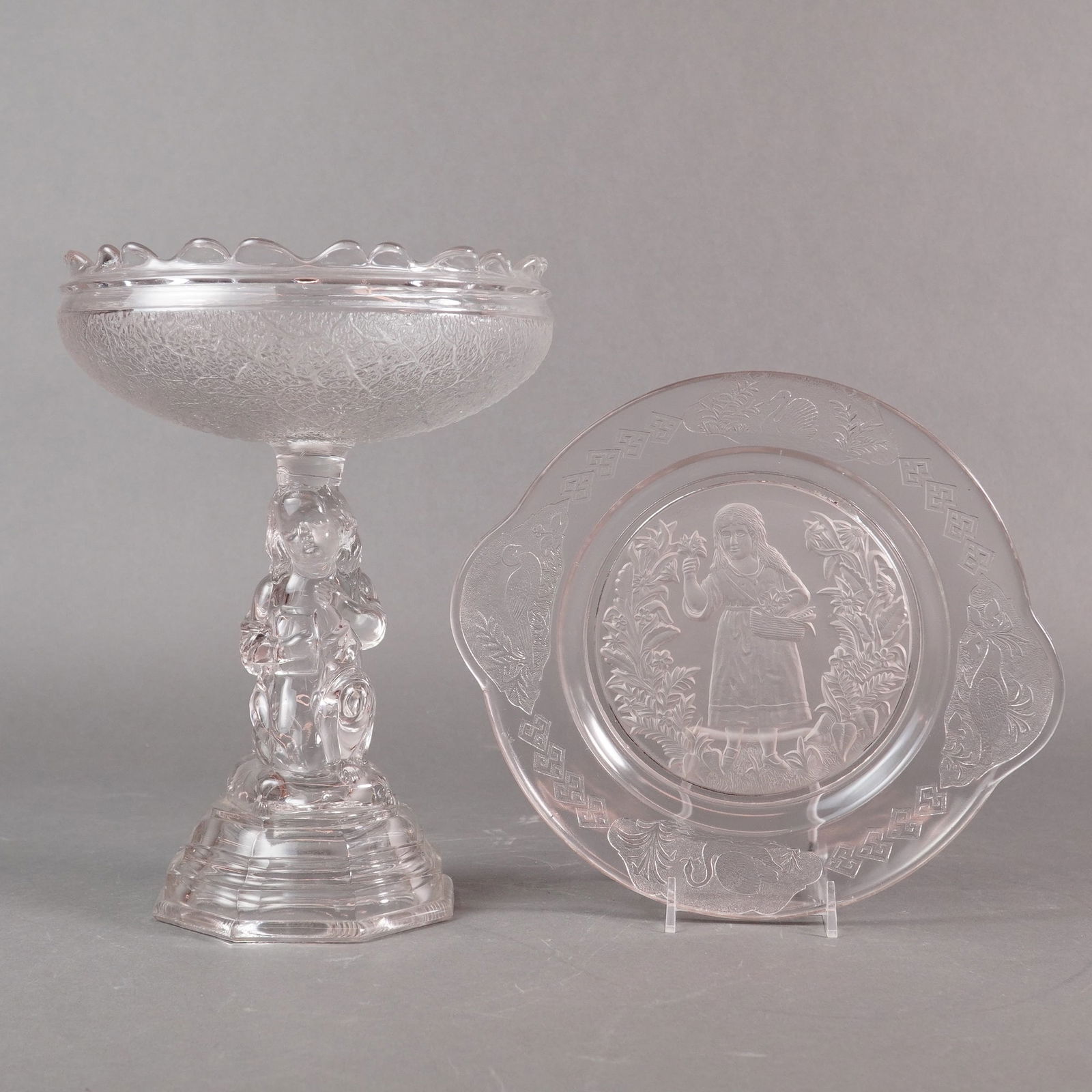 A Two-Piece Lot of EAPG Hobbs Brockunier Compote and Handled Plate: A two-piece lot of Early American Pressed Glass (EAPG) tableware rendered in a pale pink or blush amethyst hue. The collection includes a pedestal compote and a handled decorative plate. The compote