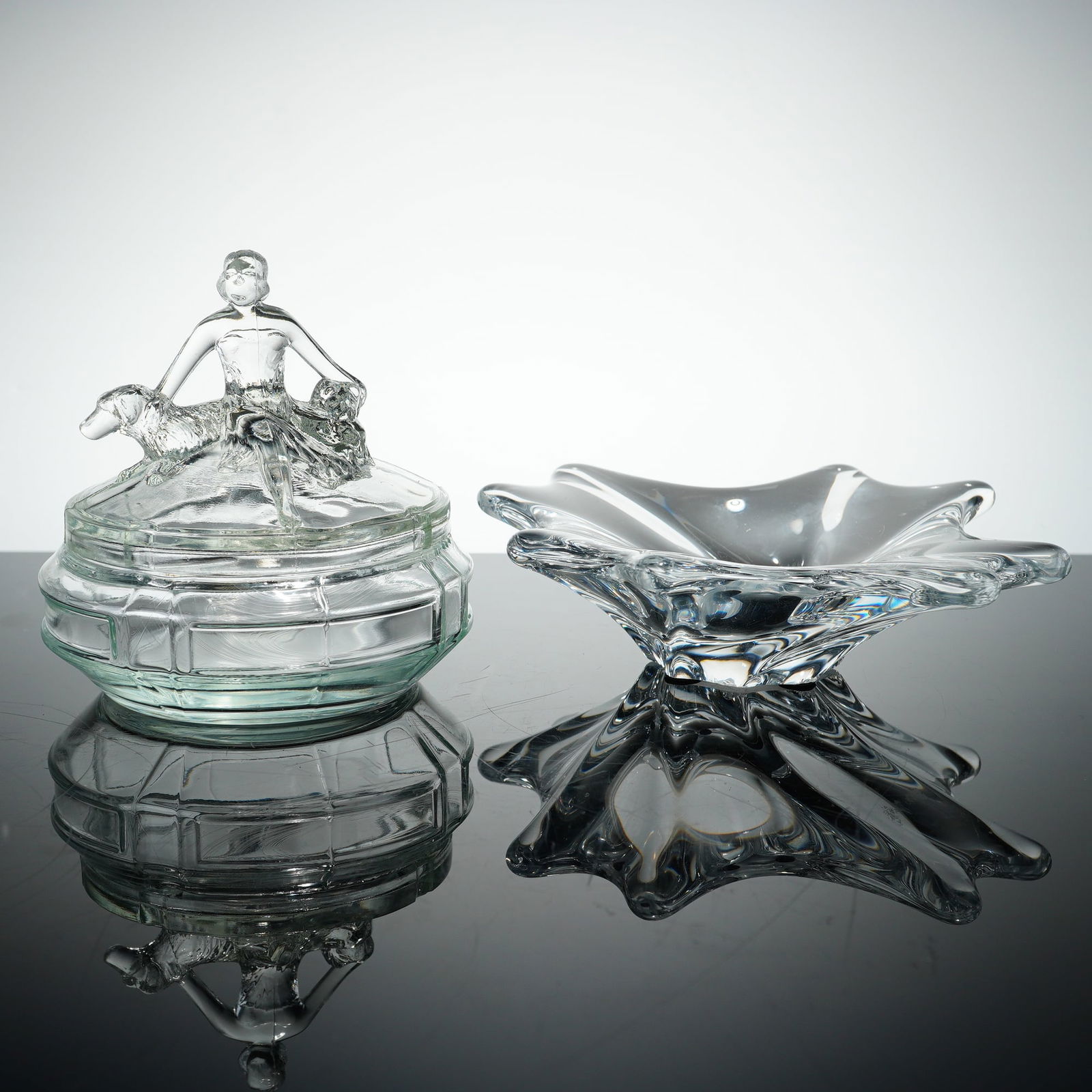 L.E. Smith Annette Powder Jar and Crystal Stretched Edge Dish: A two-piece glass and crystal grouping featuring a vintage L.E. Smith Annette clear glass powder jar and a heavy crystal stretched edge dish. The Art Deco dresser box, produced by L.E. Smith, is a