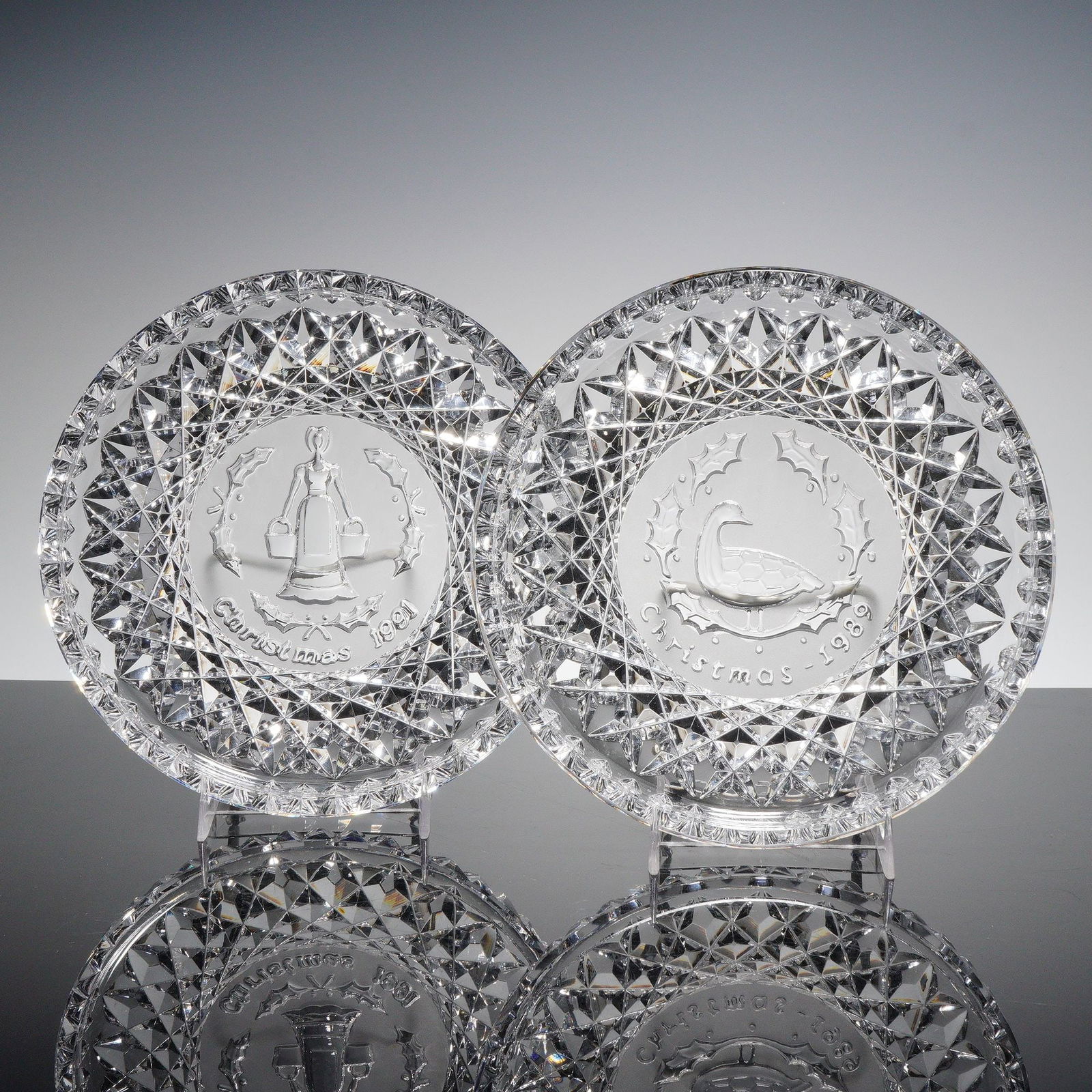 2pc Waterford Crystal 12 Days of Christmas Trays, Geese & Maids: Group of two clear pressed crystal plates from Waterford's Twelve Days of Christmas series, including Geese (1989) and Maids (1991). Each plate features a central frosted medallion with the year and
