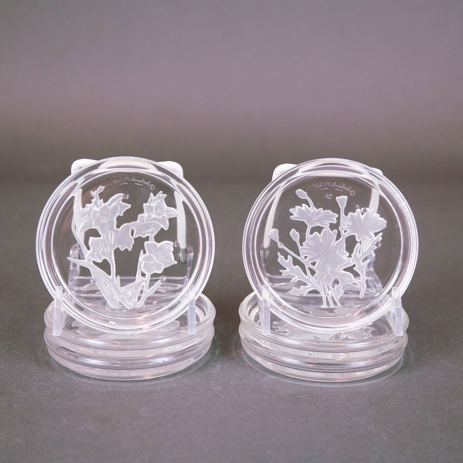 Val Saint Lambert Glass Floral Intaglio Coasters: A set of six clear glass coasters by the Belgian manufacturer Val Saint Lambert. These contemporary circular pieces feature finely detailed, frosted intaglio-carved floral motifs on the underside, inc