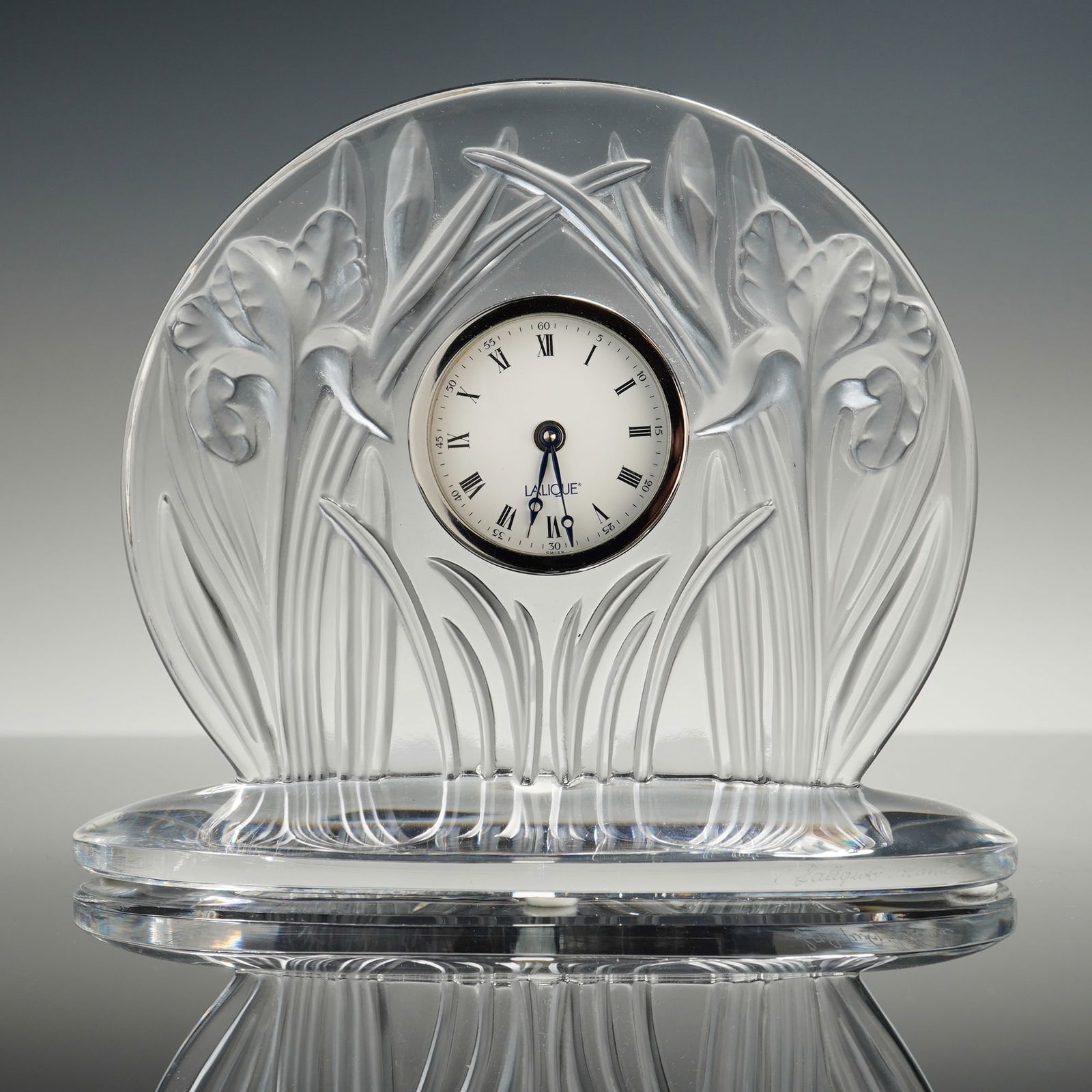 Lalique Iris Frosted and Clear Crystal Desk Clock: An elegant Lalique Iris mantel or desk clock crafted from high-quality lead crystal. This retired design features a prominent motif of two tall, dimensional iris flowers and foliage sculpted in high r