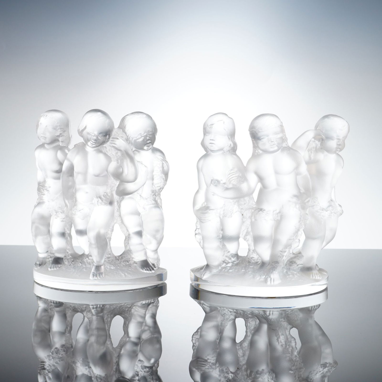 Lalique Luxembourg Cherub Bookends: A pair of Lalique French crystal Luxembourg bookends. This 2pc set features three frolicking cherubs or putti sculpted in high relief with a frosted satin finish. The figures are set upon a semi-circu