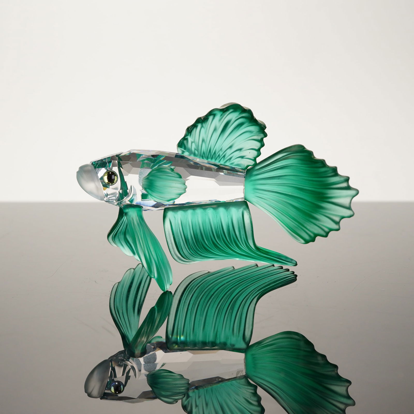 Swarovski Crystal Siamese Fighting Fish Figurine Green: A Swarovski lead crystal figurine depicting a Siamese fighting fish (Betta splendens) in a dynamic swimming pose. This piece, model number 261259 from the South Sea collection, was designed by Mario D