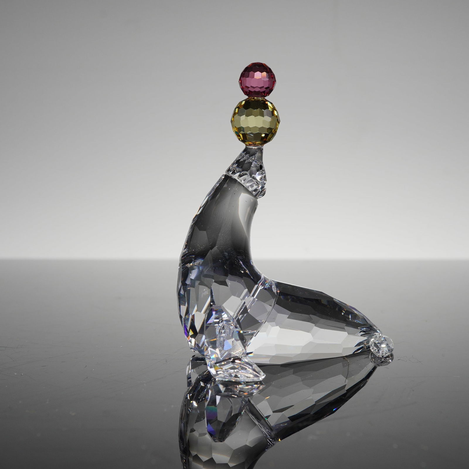 Swarovski Seal Playing Juggling Figurine 622526 Retired: This Swarovski Crystal Figurine, Seal Playing 622526, is a retired collectible from the Cheerful Times series. The piece is expertly crafted from multi-faceted clear Swarovski crystal and depicts a se