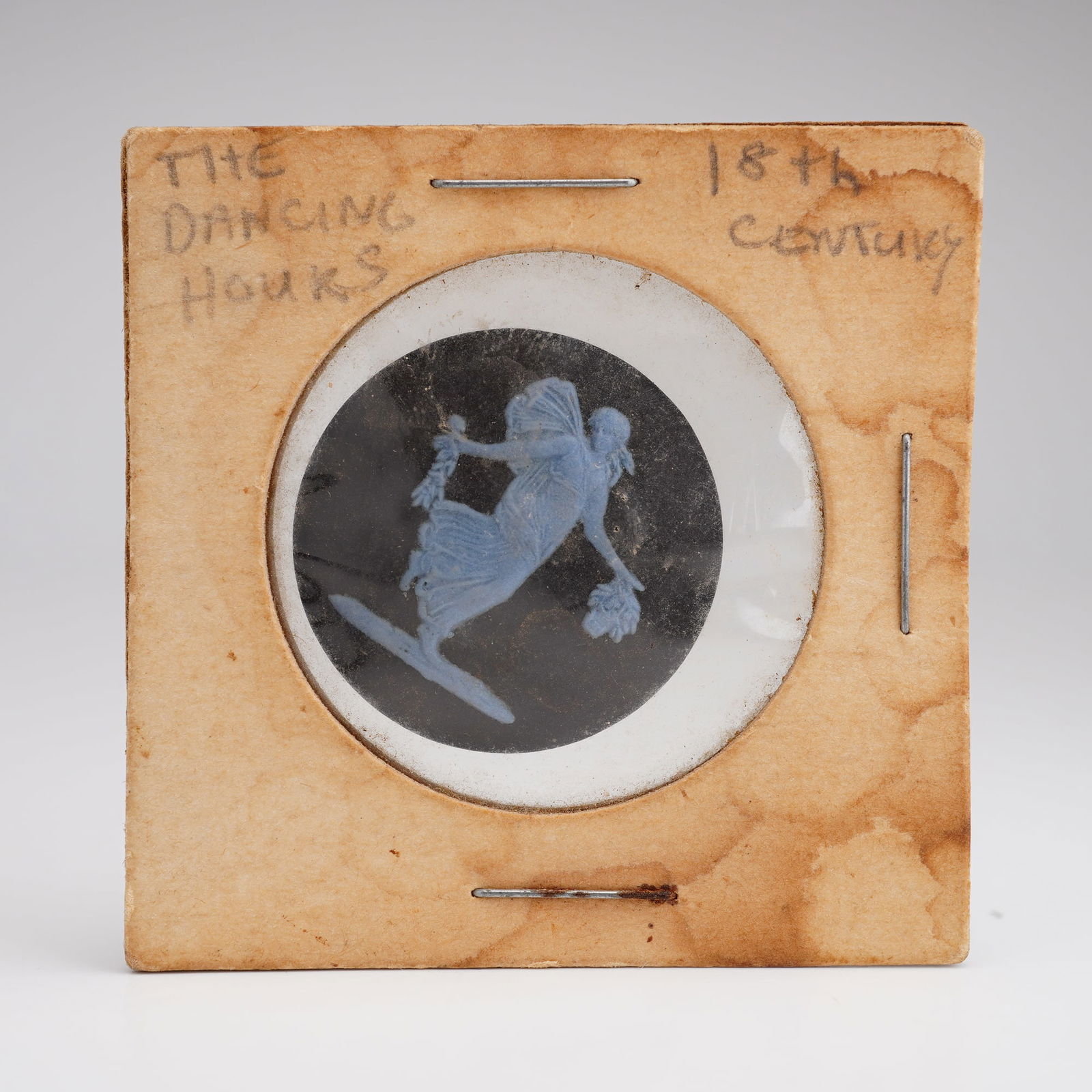 Wedgwood Black and Blue Jasperware Mini Plaque of the Dancing Hours: Circular black and blue Jasperware plaque depicting classical dancing figures. Housed in original cardboard sheaths labeled "The Dancing Hours" and "18th Century." The reverse sides are marked "Wedgwo