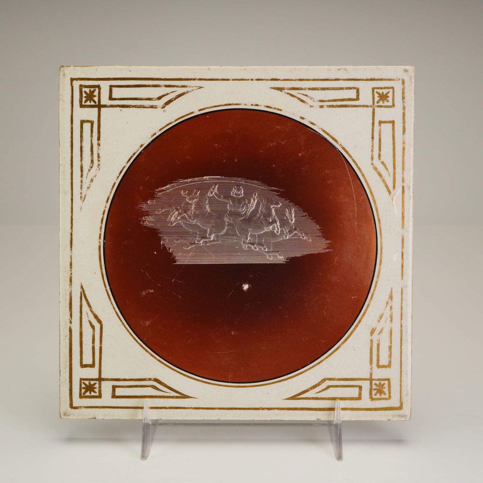 Josiah Wedgwood & Sons Etruria Etched Horses Ceramic Tile: Josiah Wedgwood & Sons produced this ceramic tile at the Etruria works, featuring a central circular field in deep terracotta red. The etched scene depicts stylized horses in motion, rendered through