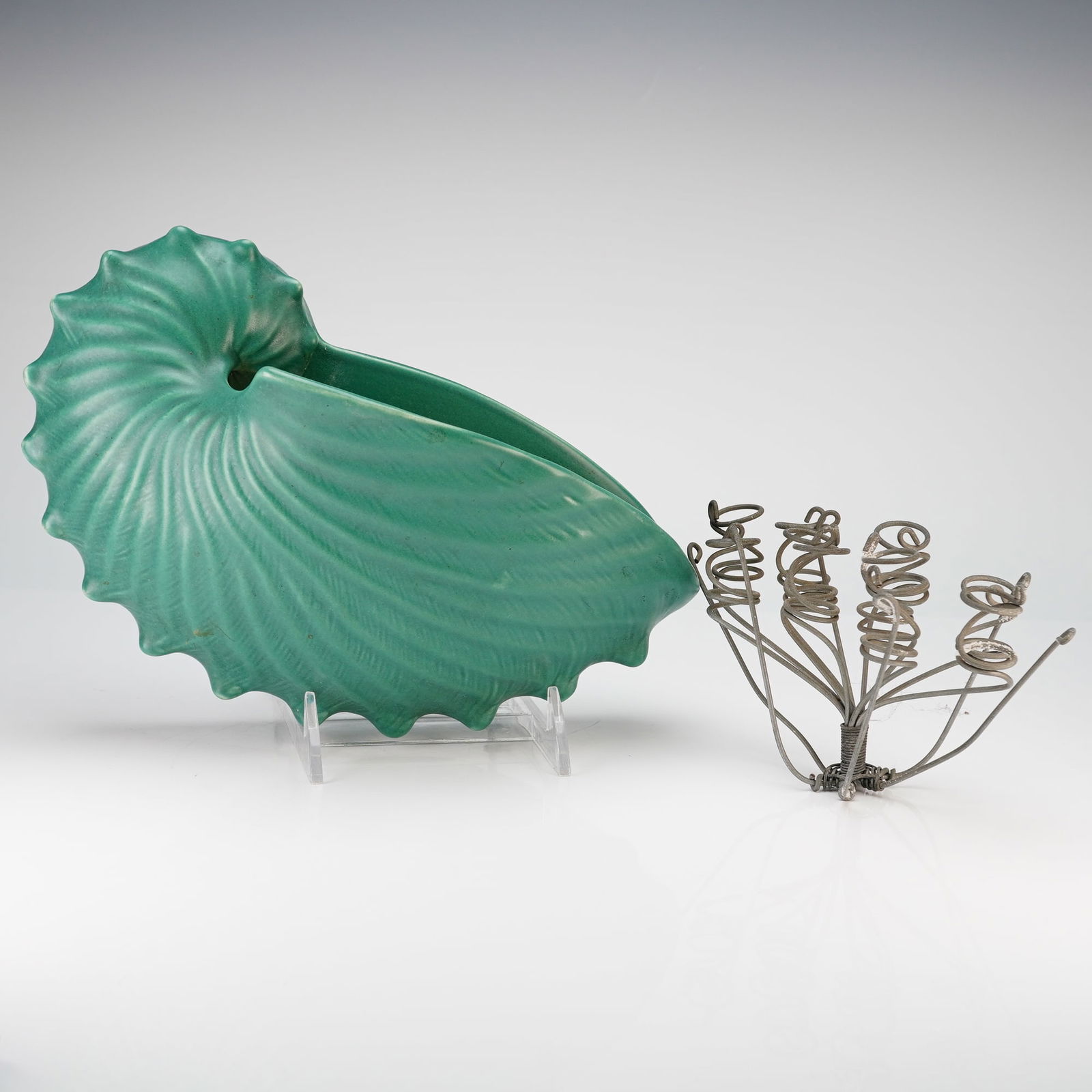 Two Wedgwood Matt Green Ceramic Nautilus Shell Wall Pocket and Flower Frog: A Wedgwood ceramic wall pocket and an accompanying metal wire flower frog. The wall pocket is modeled in the form of a nautilus shell and finished in a matte green glaze. The reverse of the ceramic pi