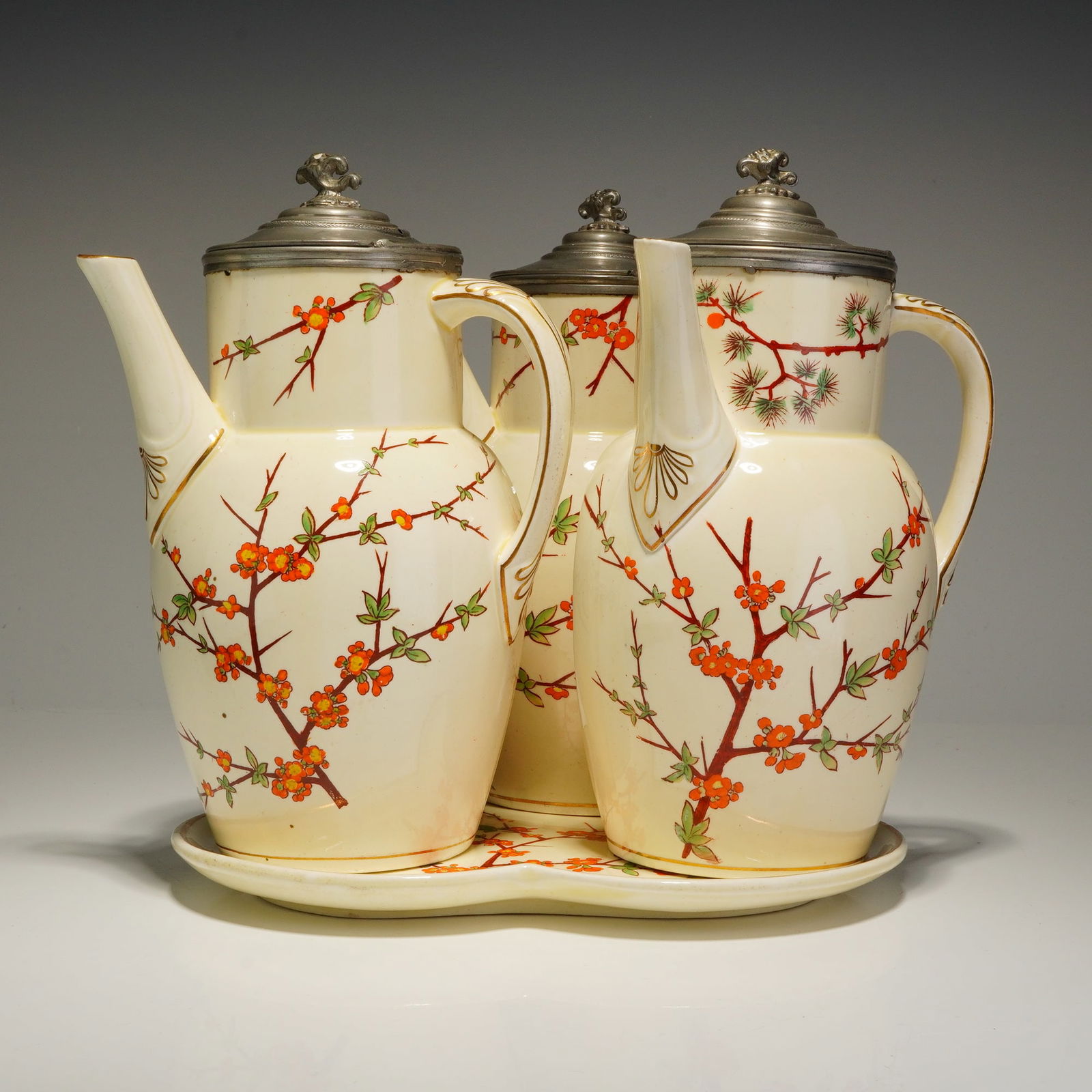 A 4pc Wedgwood Lot of Three Lidded Coffee Pots with Tray: This 4pc Wedgwood lot comprises three lidded coffee pots and a matching trefoil-shaped tray. The ceramic set features a cream-colored ground decorated with hand-painted East Asian-inspired motifs of f