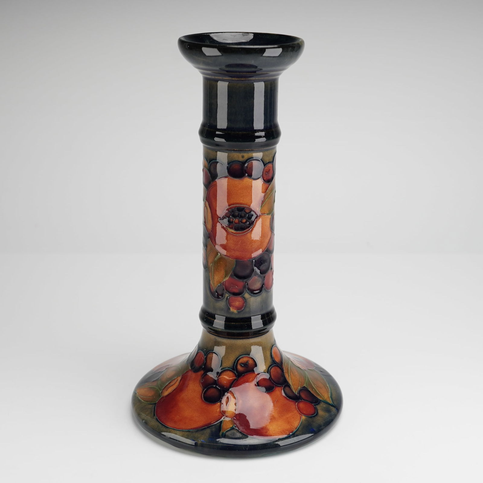 Moorcroft Pottery by William Moorcroft Candlestick Pomegranate: William Moorcroft candlestick decorated in the Pomegranate pattern with open pomegranates to the stems, signed and impressed marks to bases Dimensions4.50"W x 8.50"H