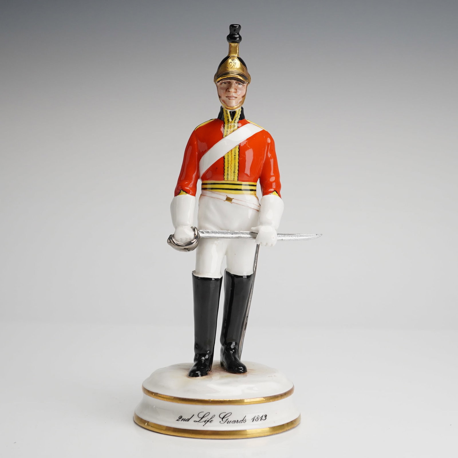 Michael Sutty Porcelain Figurine 2nd Life Guards 1813: A single porcelain figurine by Michael Sutty Porcelain Manufacturers, depicting a standing British military officer, specifically a member of the 2nd Life Guards in an 1813 uniform. The figure is rend