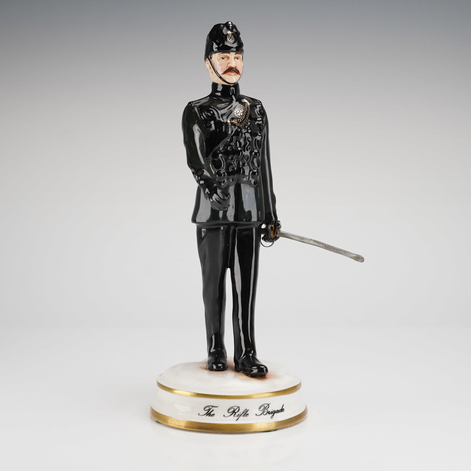 Michael Sutty Porcelain Figurine The Rifle Brigade: A single, hand-painted glazed porcelain figurine attributed to Michael Sutty, depicting an officer of The Rifle Brigade. The figure wears a highly detailed, high-gloss uniform in black or very dark gr
