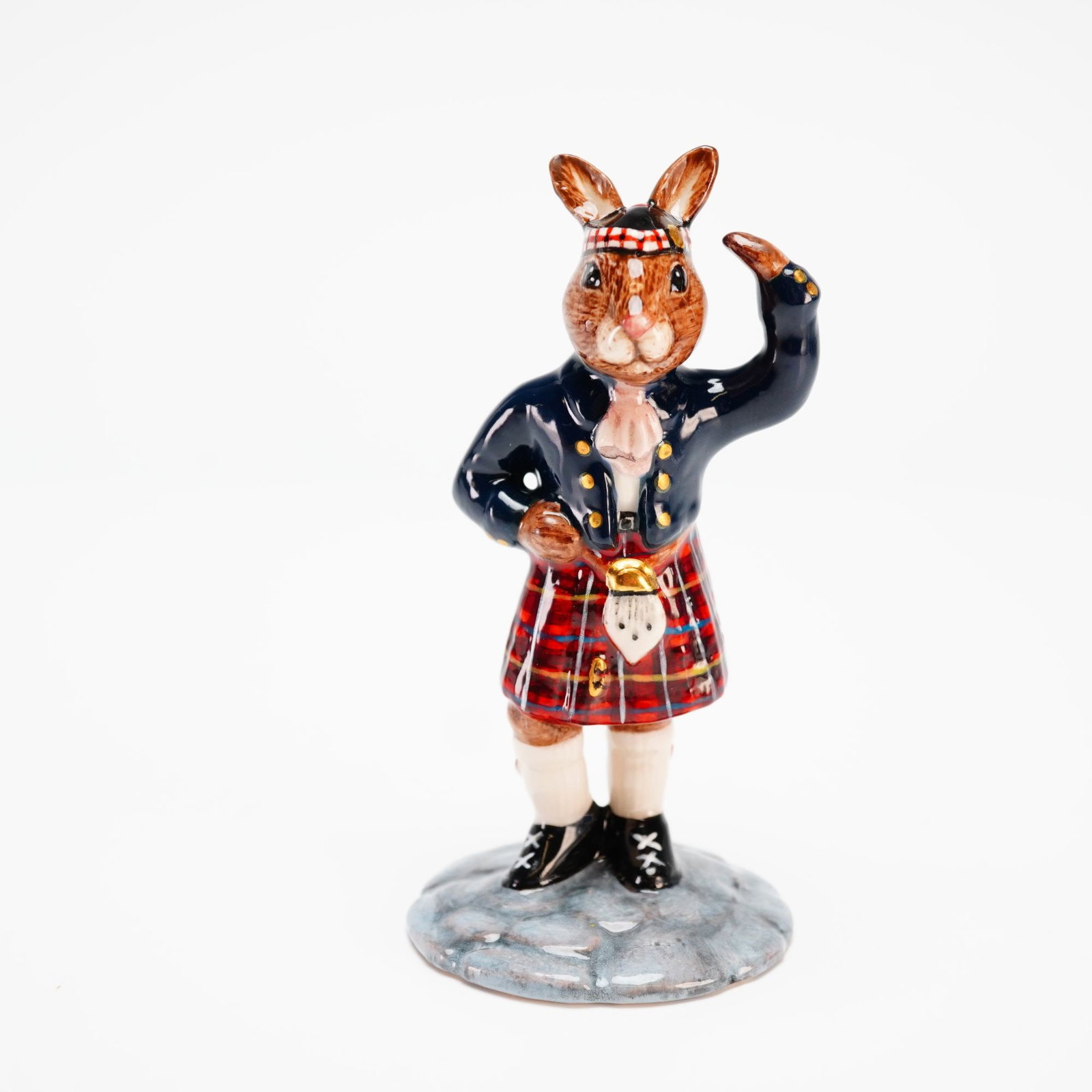 Royal Doulton Prototype Scotsman Bunnykins Figurine: Intricately decorated prototype Scotsman Bunnykins in a dark blue Highland jacket with gold buttons, topped by a black Glengarry hat with a red-and-black diced band, a gold badge, and a red pom on top
