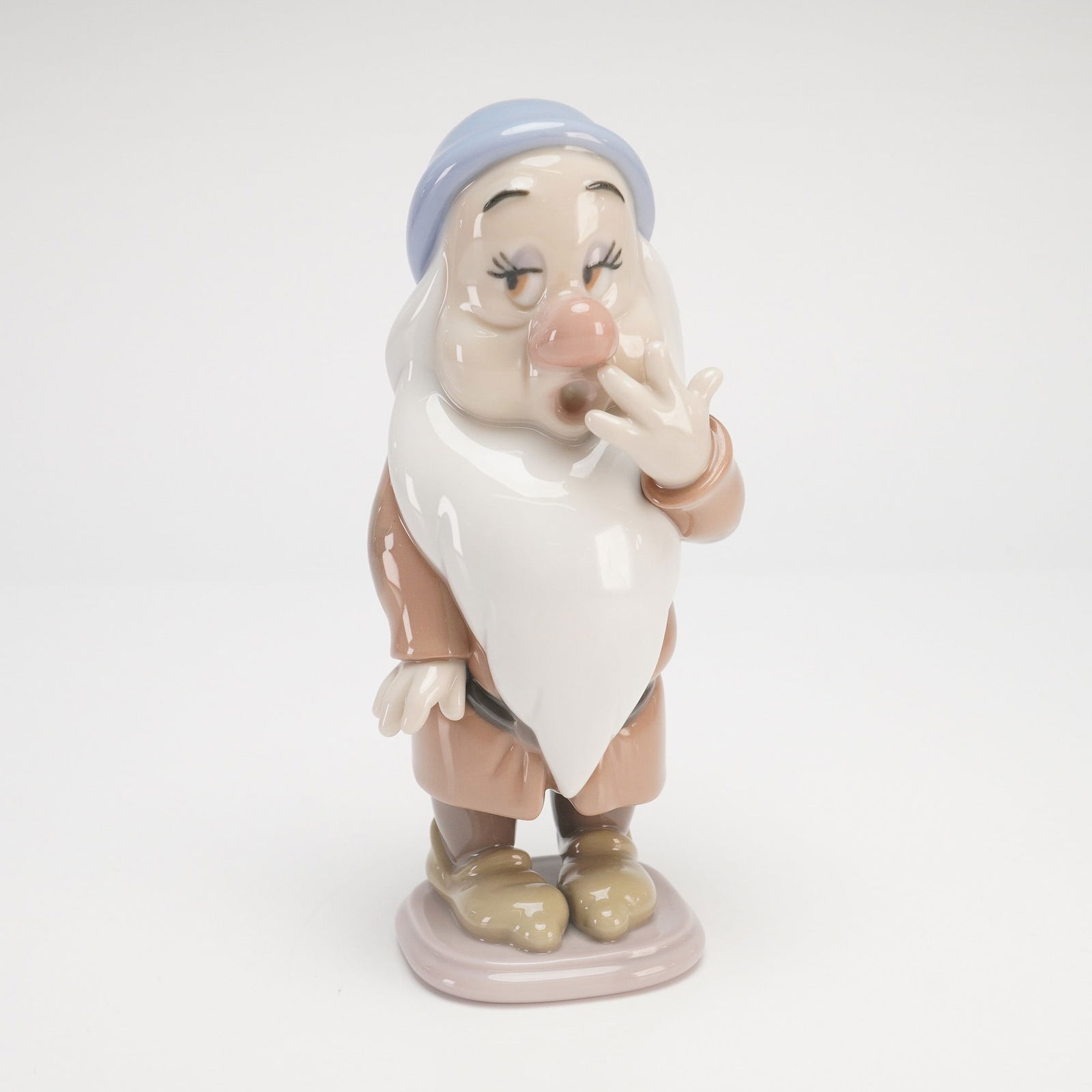Lladro Disney Sleepy Dwarf #7539: A Lladro glossy figurine model 7539 of Sleepy, one of the seven dwarfs from Walt Disney's Snow White and the Seven Dwarfs. The character is depicted in a classic pose, yawning with his right hand rais