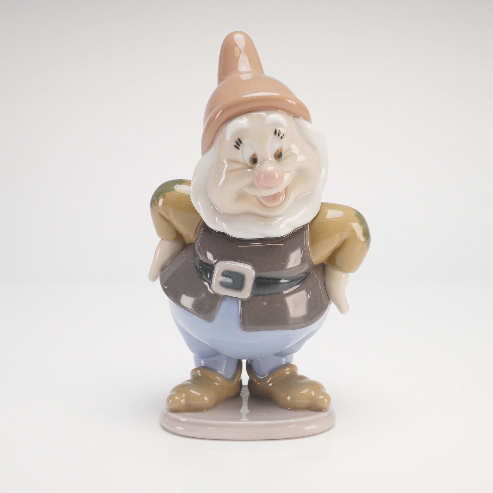 Lladro Disney Happy Dwarf Figurine #7537: A Lladro glossy figurine model 7537 depicting the character Happy from Walt Disney's Snow White and the Seven Dwarfs. This hand-painted porcelain figurine features the character in a jovial pose with