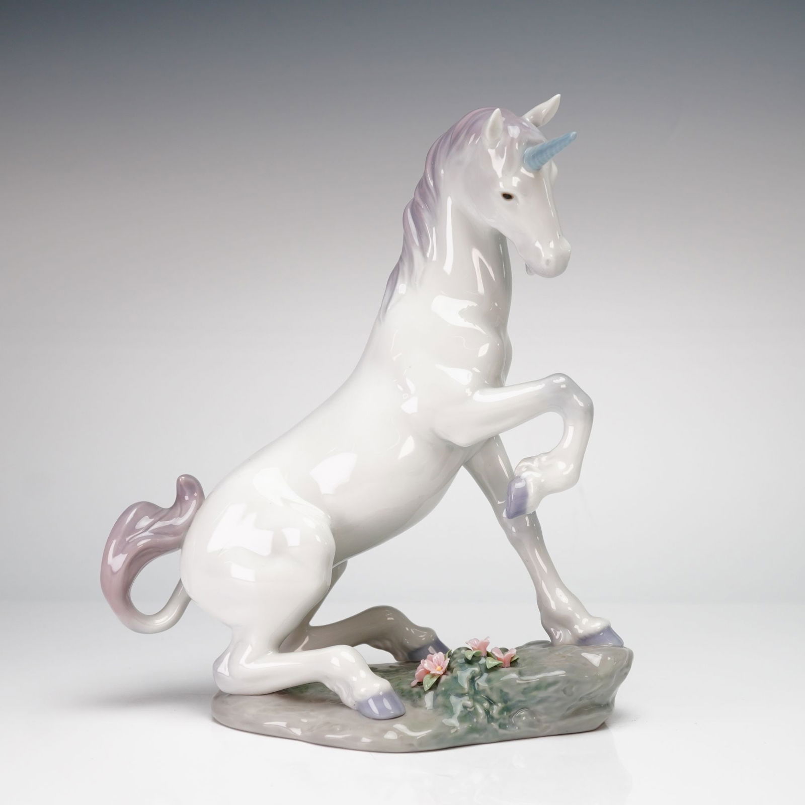 Lladro Magical Unicorn Privilege Figurine #1007697: This Lladro Privilege glazed porcelain figurine, titled Magical Unicorn (model 1007697), depicts a mythical unicorn in a rearing pose upon a rocky base. The base is intricately detailed with
